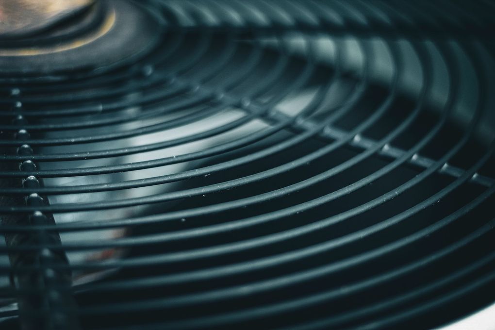 Close-up of a dark metal fan grille with curved concentric blades