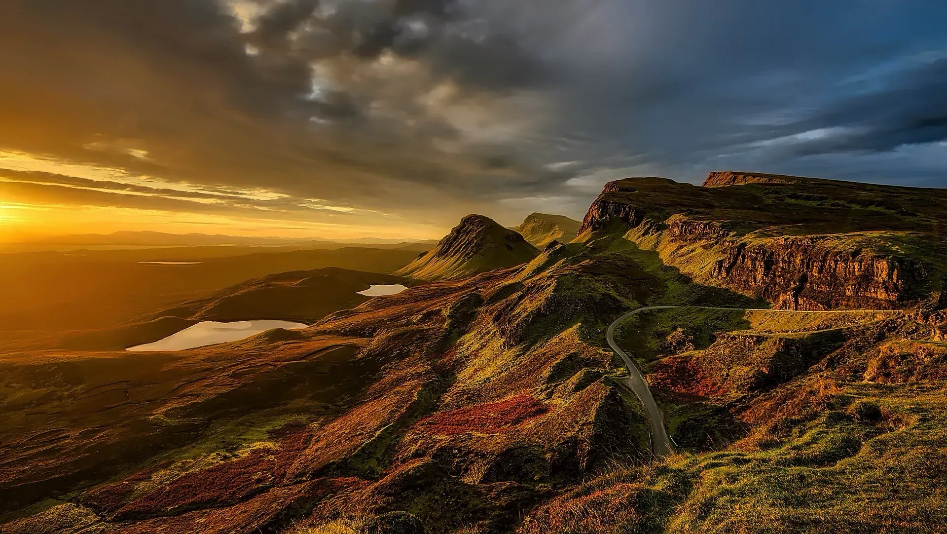Sunset over rocky coastal cliffs with golden light and dramatic clouds