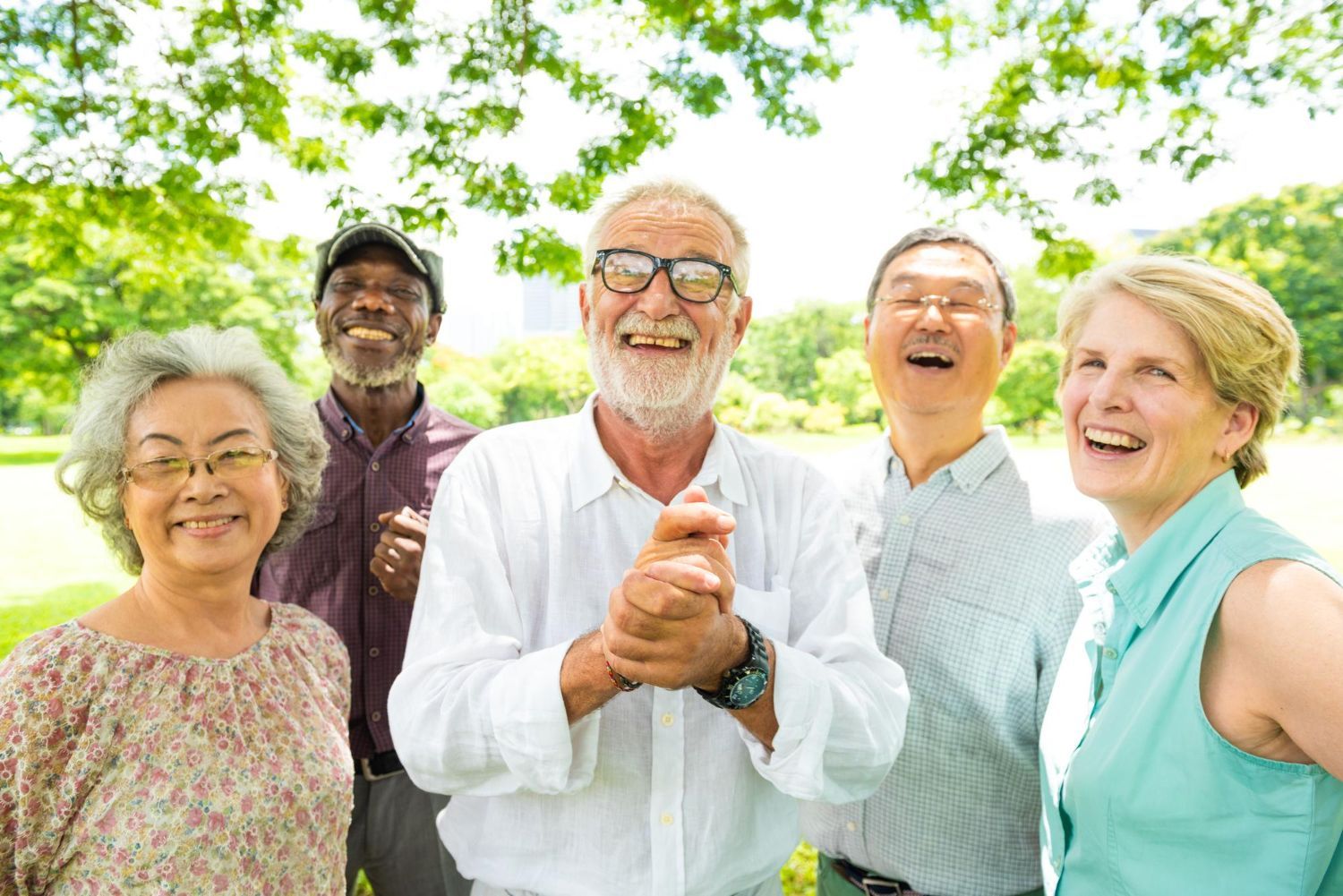 Group of diverse seniors smiling outdoors in a park; sunny day.