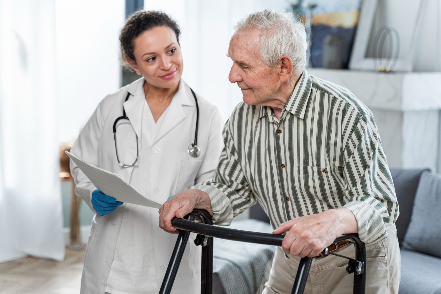 Doctor assisting elderly man using a walker, indoors. Both looking at papers, smiling.