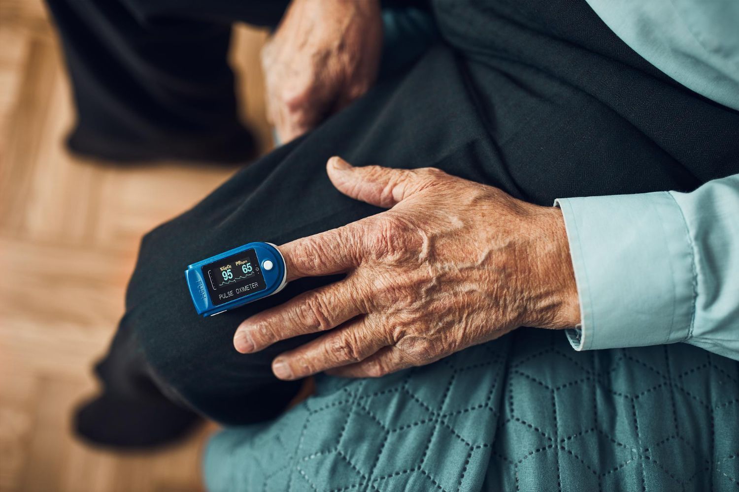 A pulse oximeter on an elderly person's finger, measuring oxygen levels.