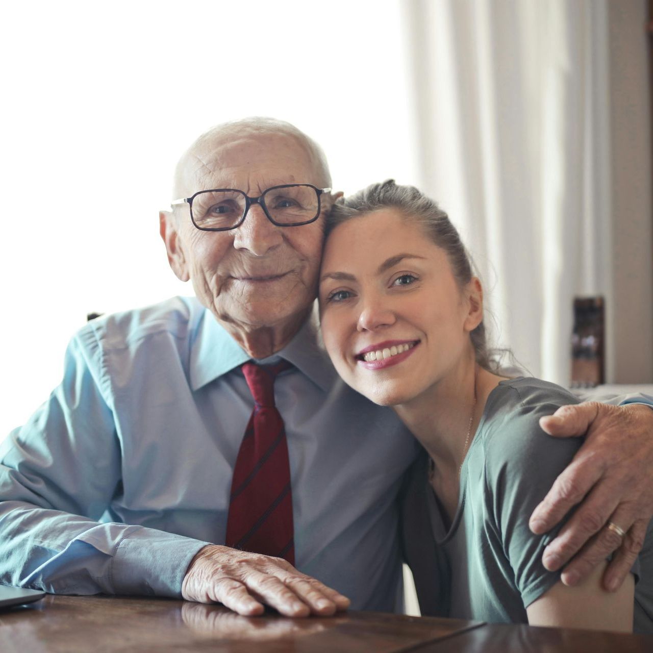 An elderly man and a young woman are posing for a picture.