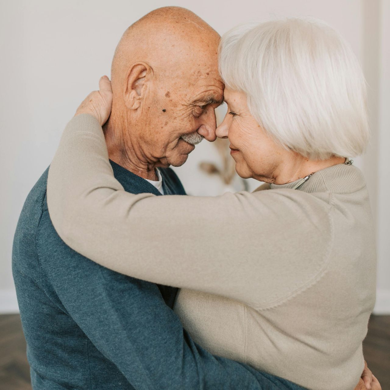 A man and a woman are hugging each other and looking at each other.