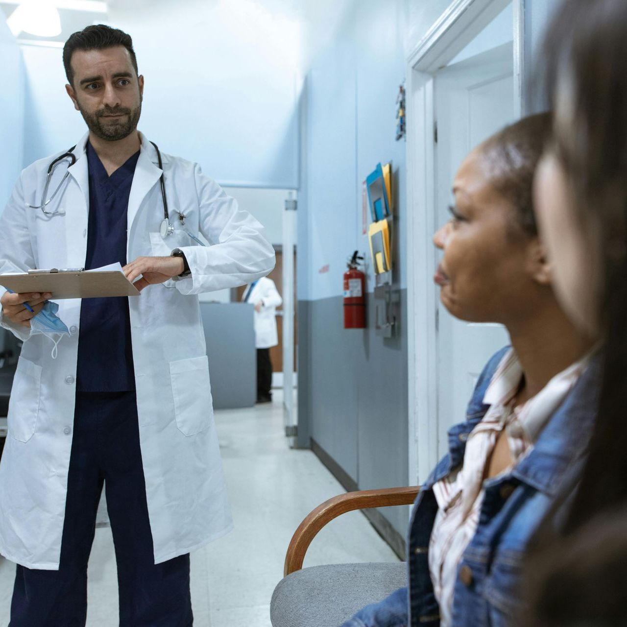 A doctor is talking to a patient in a hospital hallway