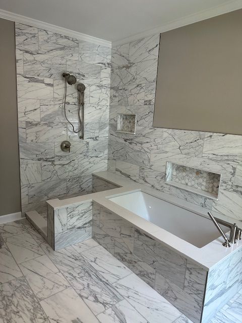 A modern bathroom featuring a white marble walk-in shower and a built-in soaking tub with matching marble tile surfaces.