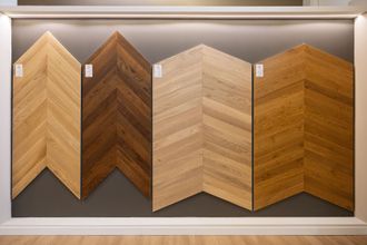 Esposizione di quattro campioni di pavimento in legno con motivo a spina di pesce in uno showroom