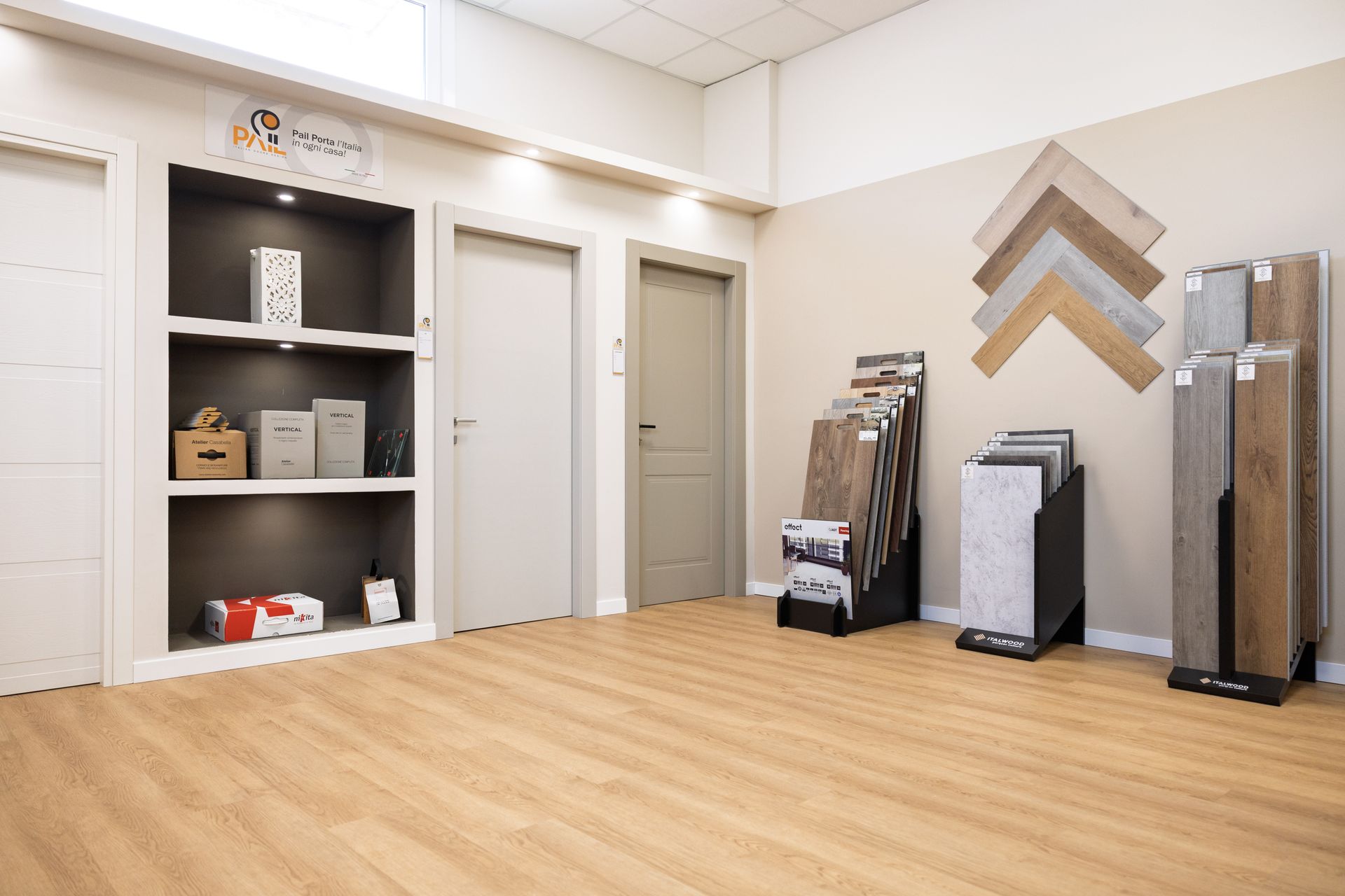 Showroom con pavimento in legno, scaffali, porte e pannelli espositivi per campioni