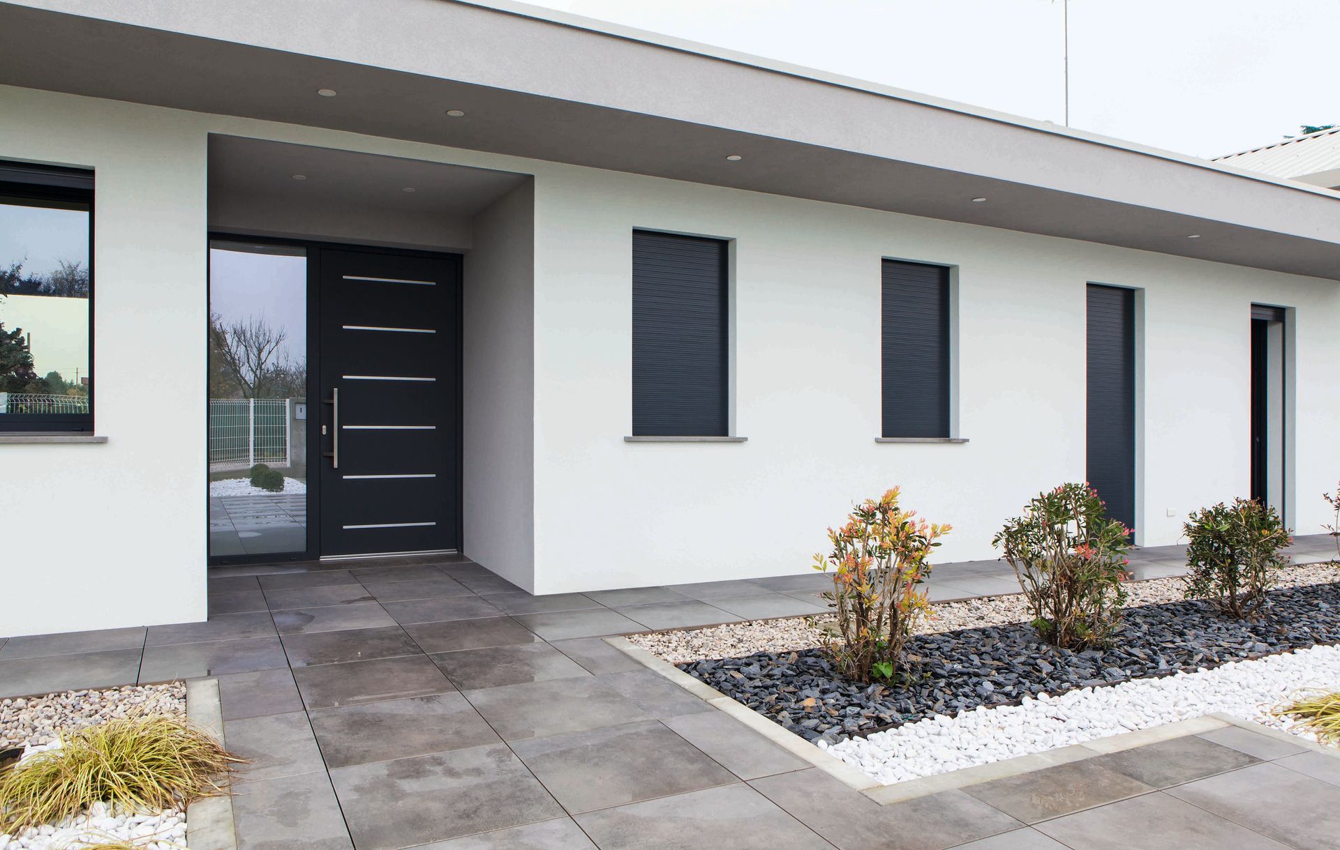 Esterno di una casa moderna con pareti bianche, porta d'ingresso scura