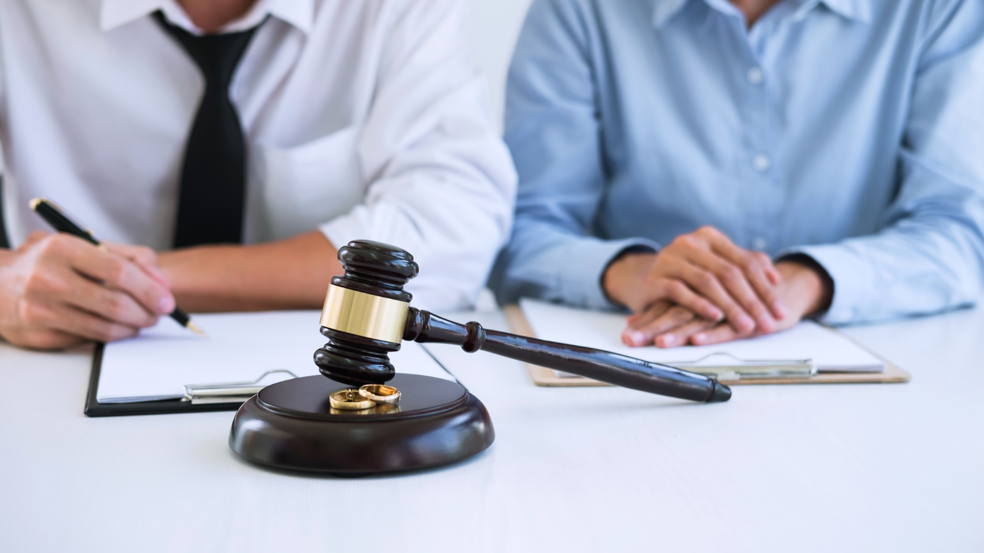 Lawyer’s gavel on desk in front of two people signing documents in an office
