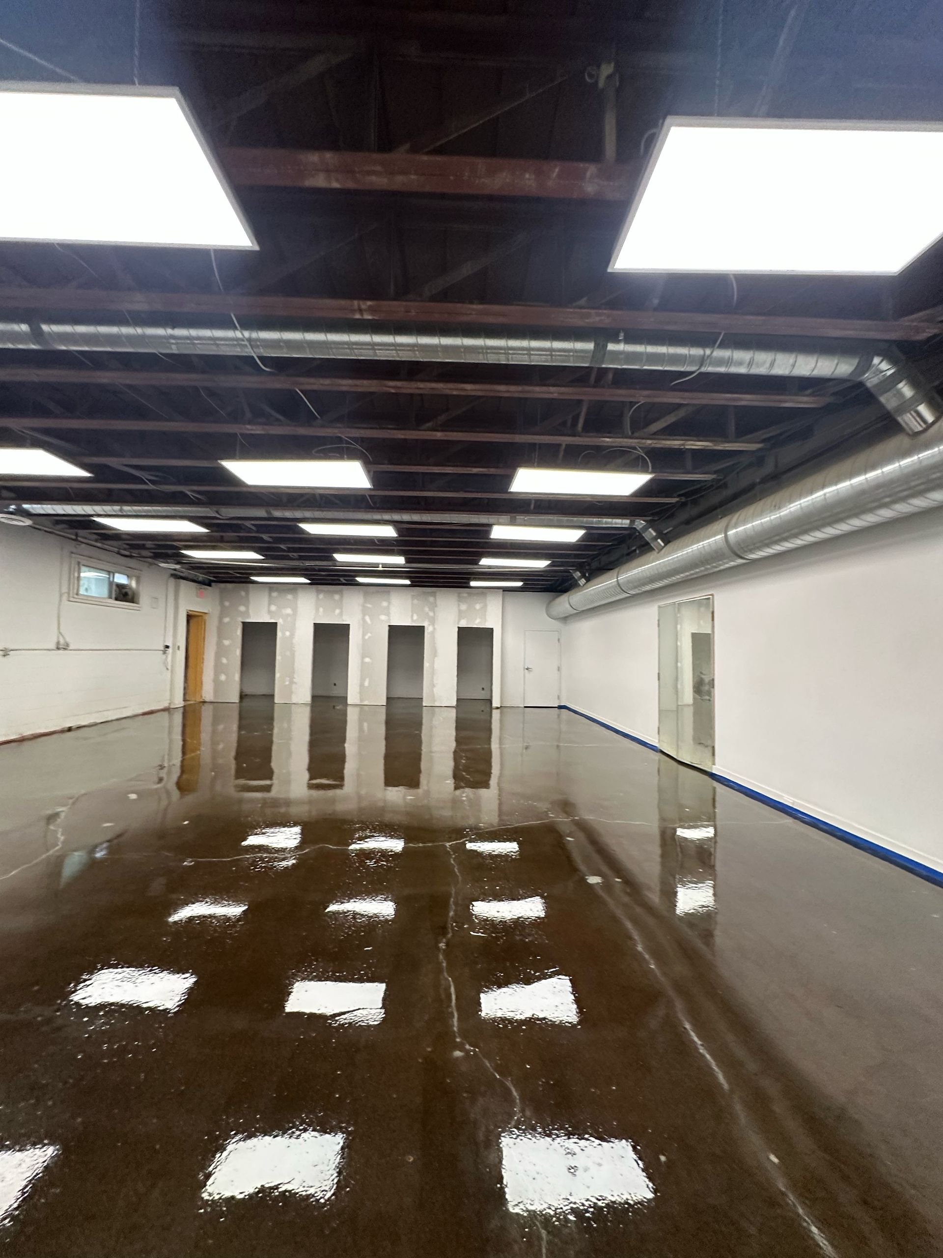 Empty flooded industrial room with reflective water on the floor and fluorescent ceiling lights