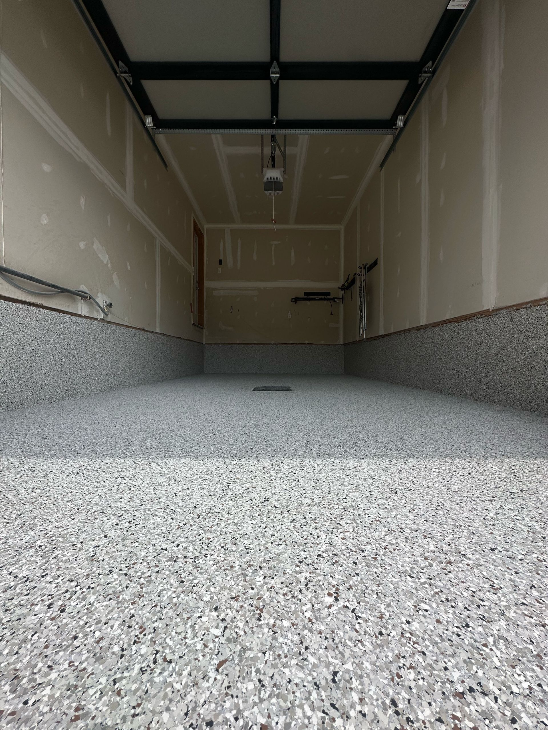 Empty garage interior with speckled floor and unfinished walls