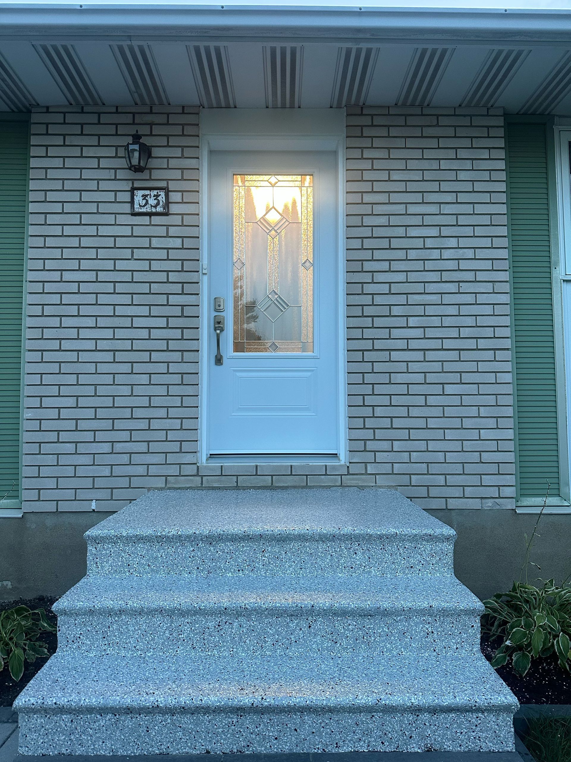 Front entrance of a brick house with a white door and stone steps leading up to it.