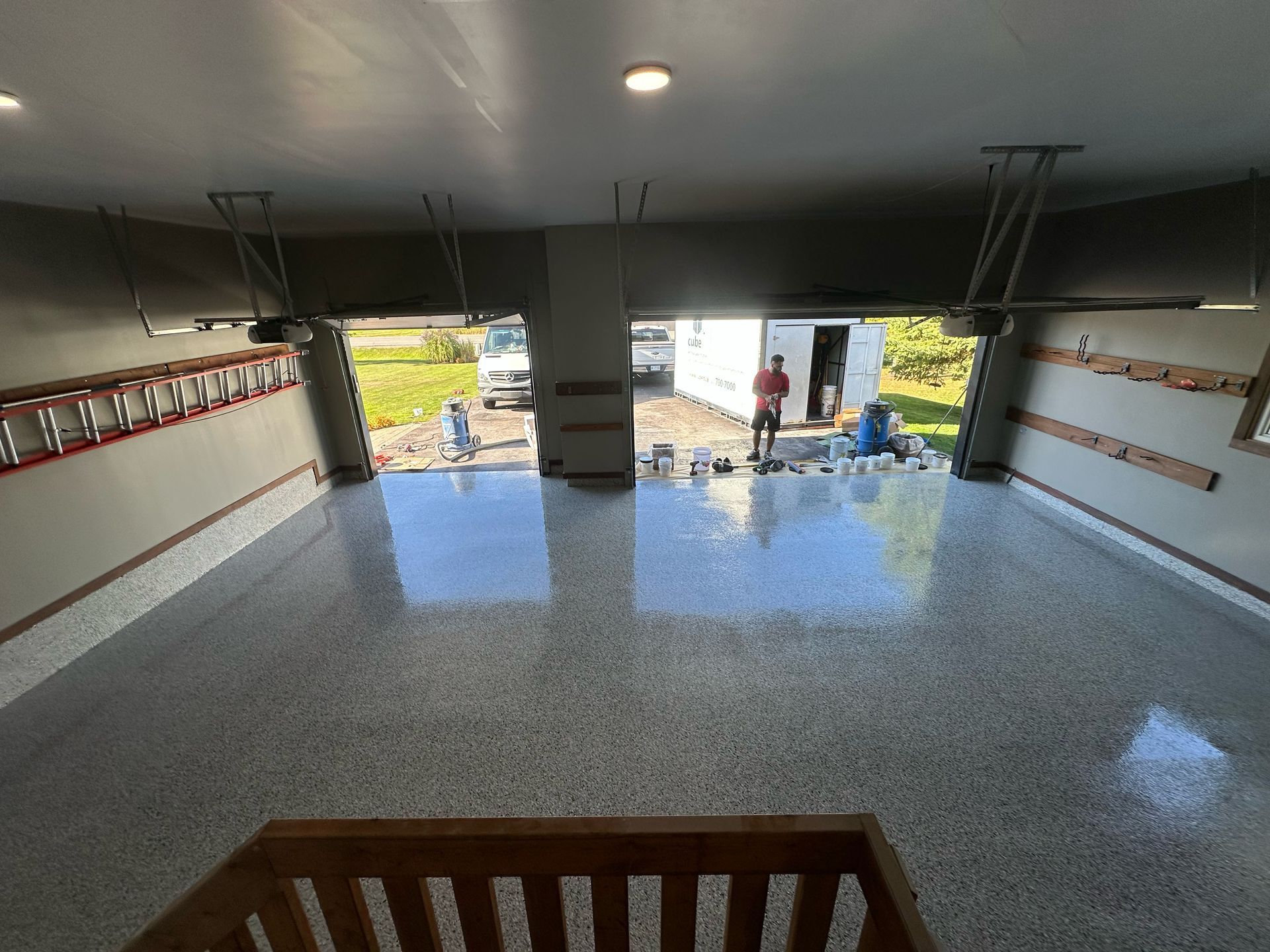 Garage interior with glossy speckled floor, open door, and people working outside