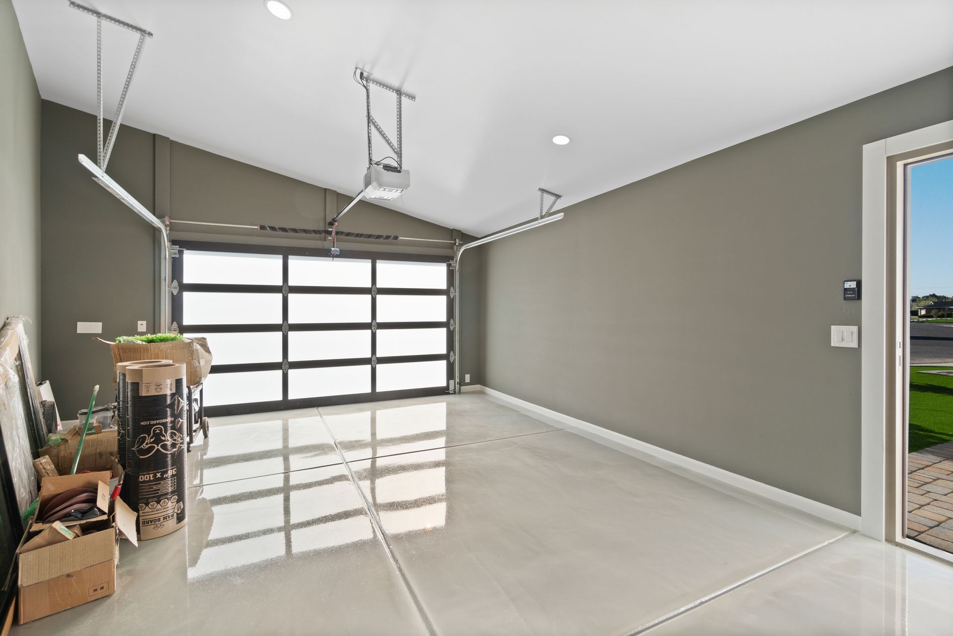 An empty garage with a glass garage door and a sliding glass door.