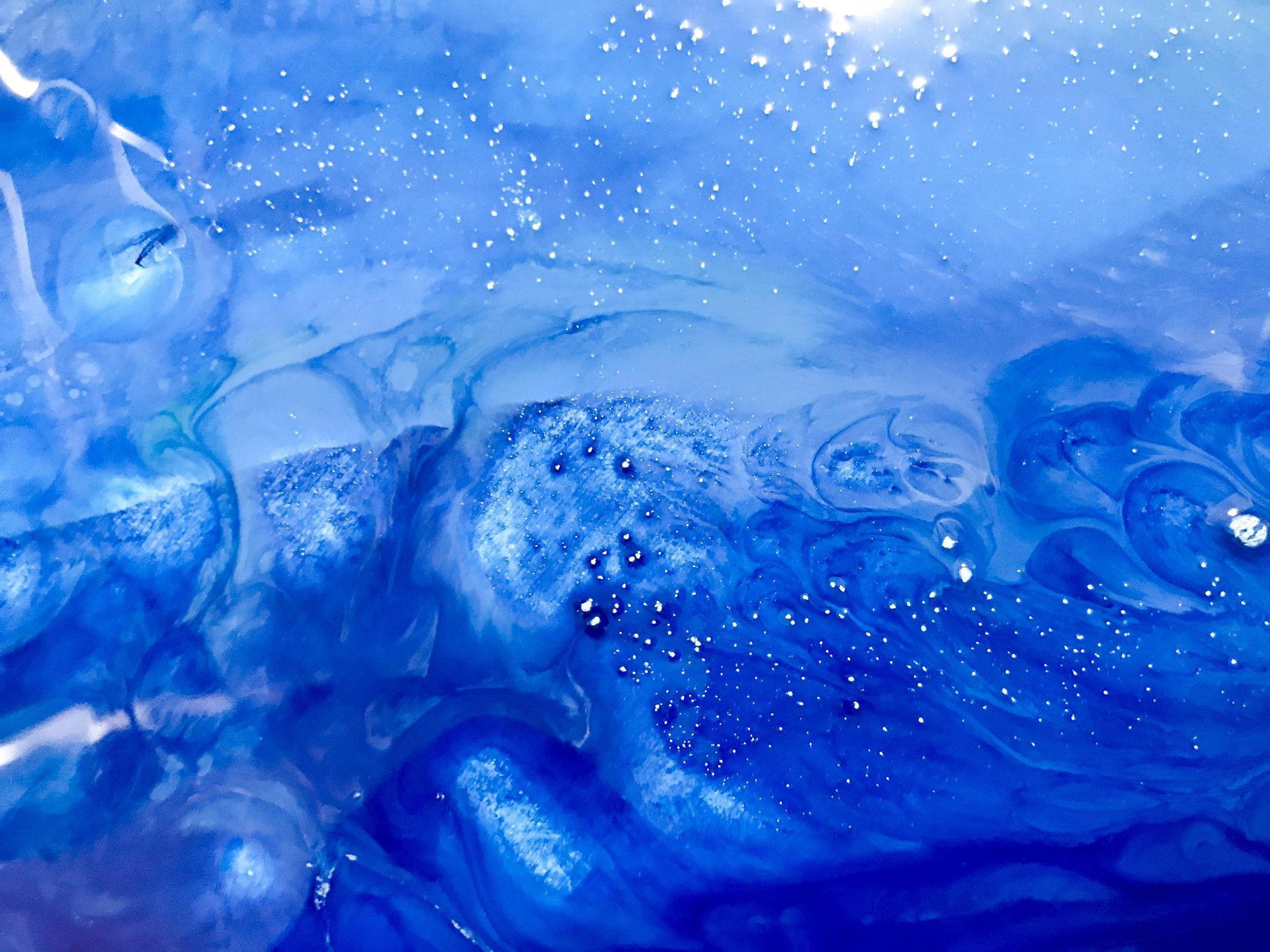 A close up of a blue liquid with bubbles in it.