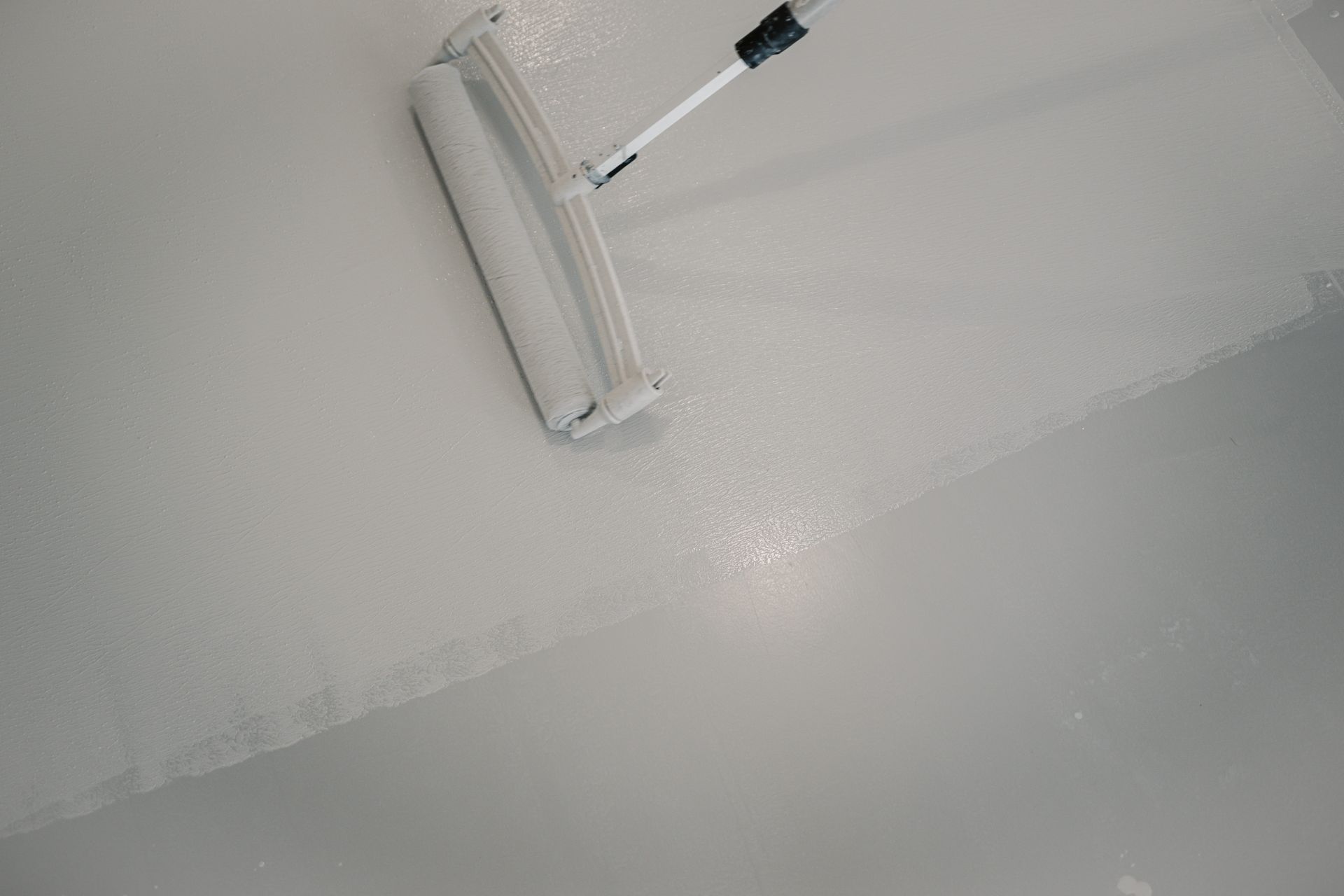 Une personne peint un sol avec un rouleau.