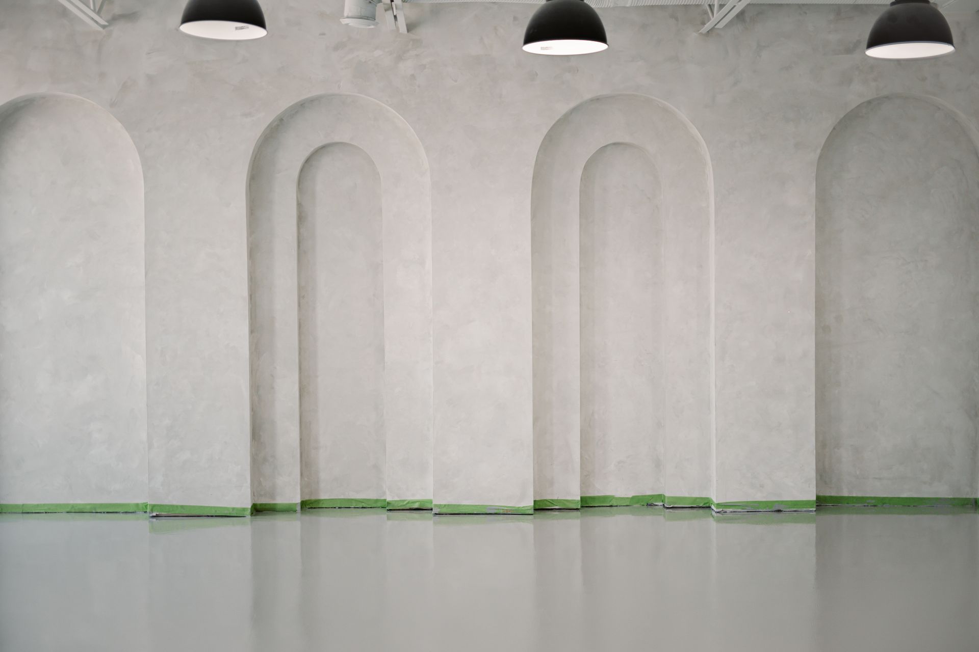 Une pièce vide avec des arches sur les murs et un sol en béton.