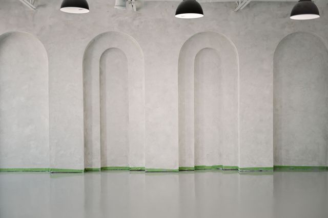 An empty room with arches on the walls and a concrete floor.