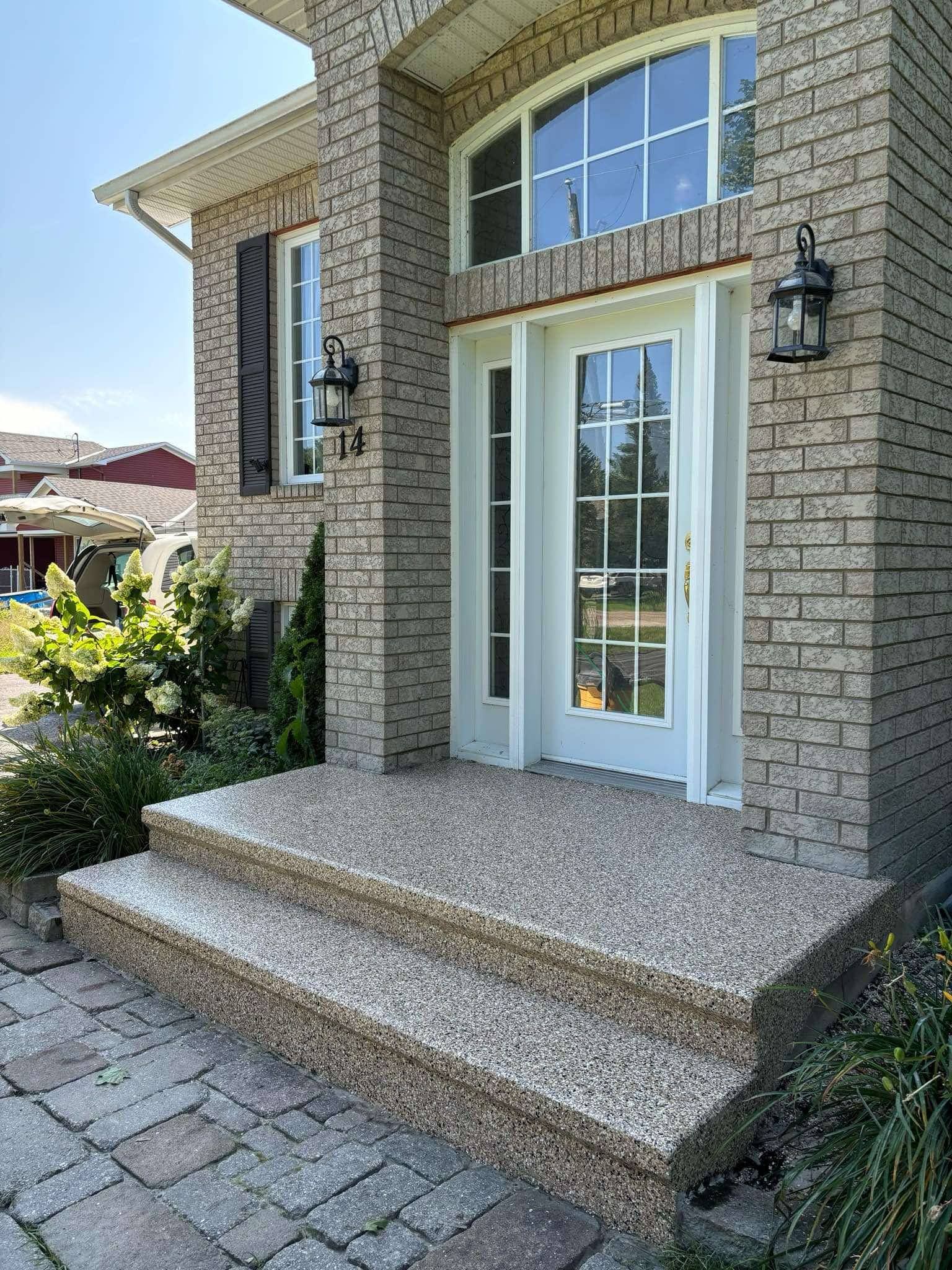 Stone house front entrance with steps, white glass door, arched window, and wall-mounted lanterns