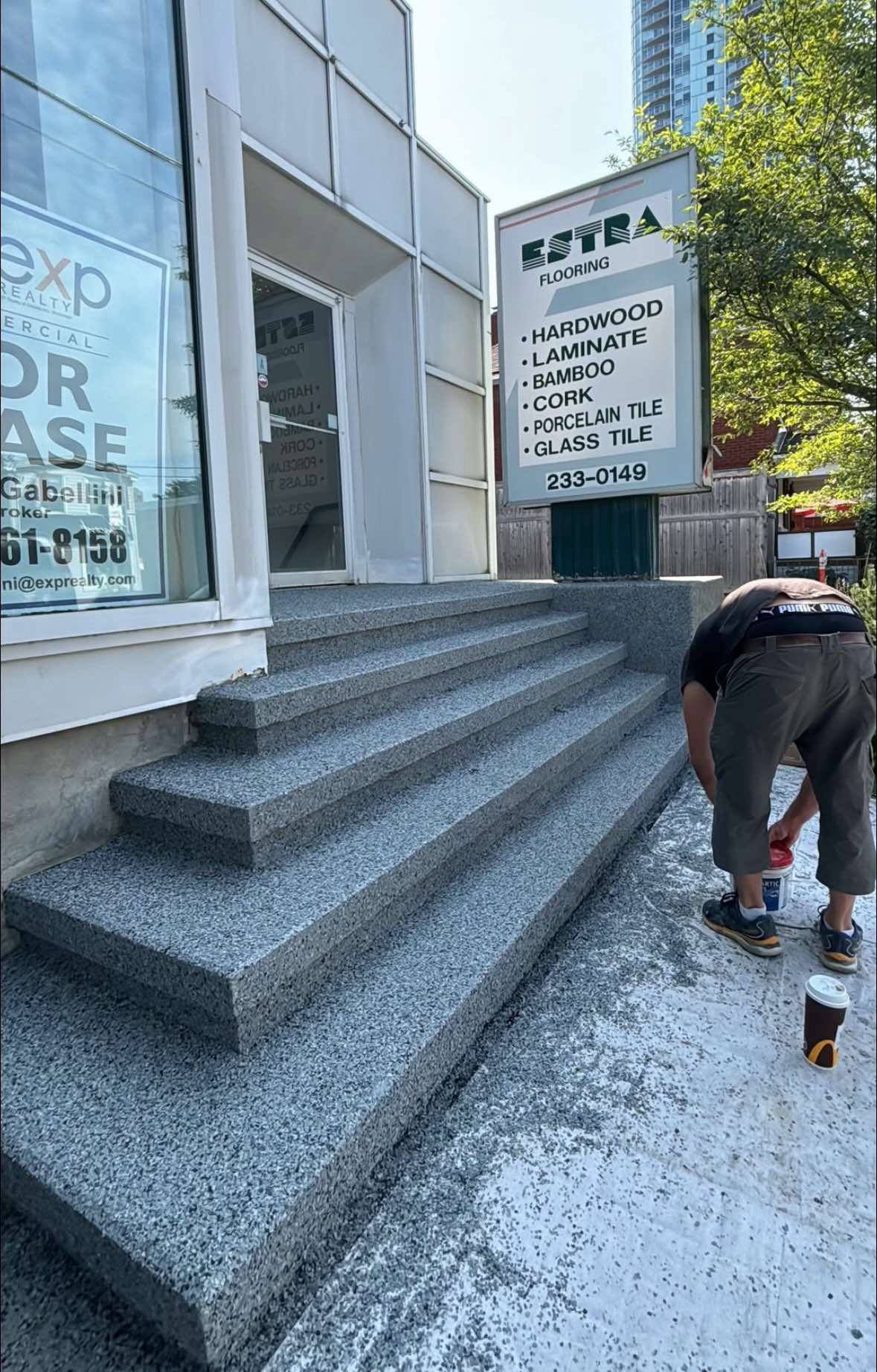 Person bending near stone steps outside a building with Japanese signage.