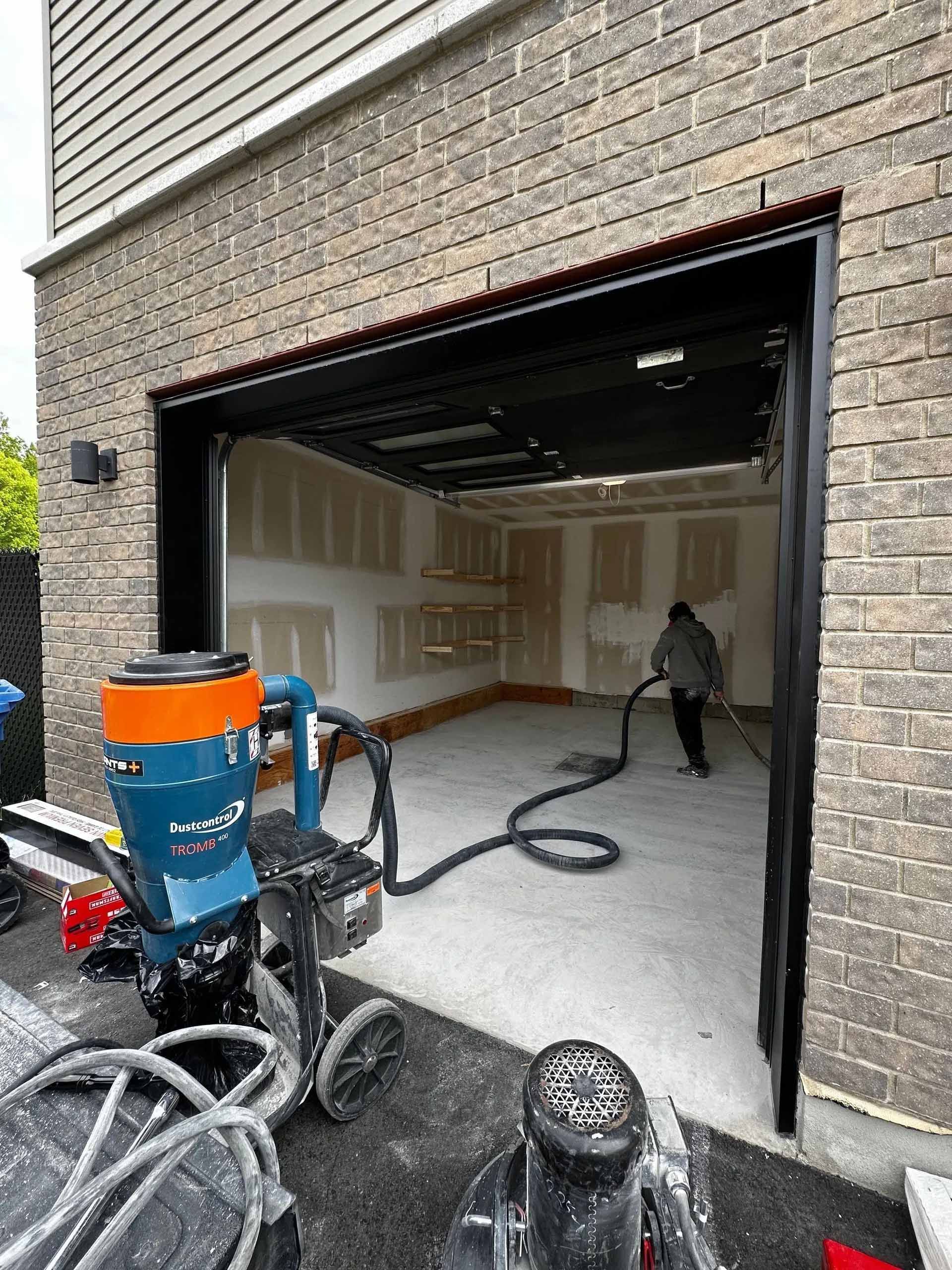 Un homme nettoie un garage avec un aspirateur.