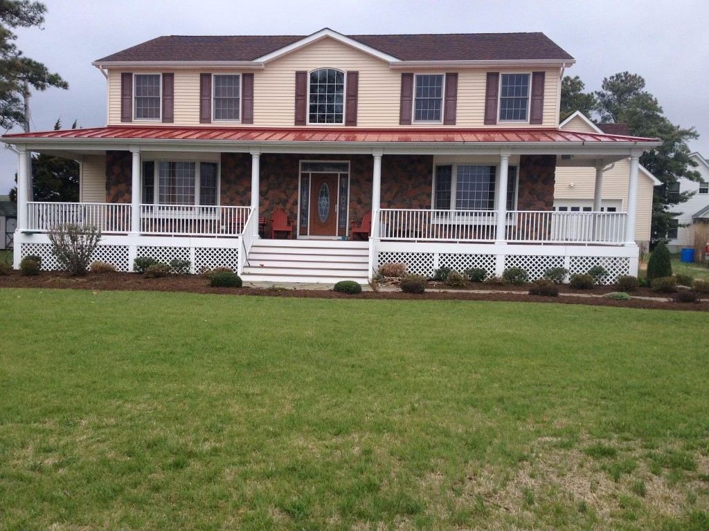 A large house with a large porch and a red roof