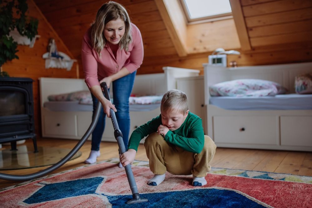 Woman Vacuuming Carpet With Child — Side By Side Support Services Casino in Casino, NSW