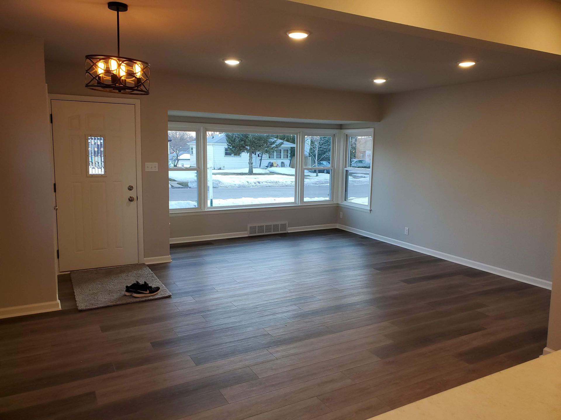 an empty living room with hardwood floors and a chandelier hanging from the ceiling .