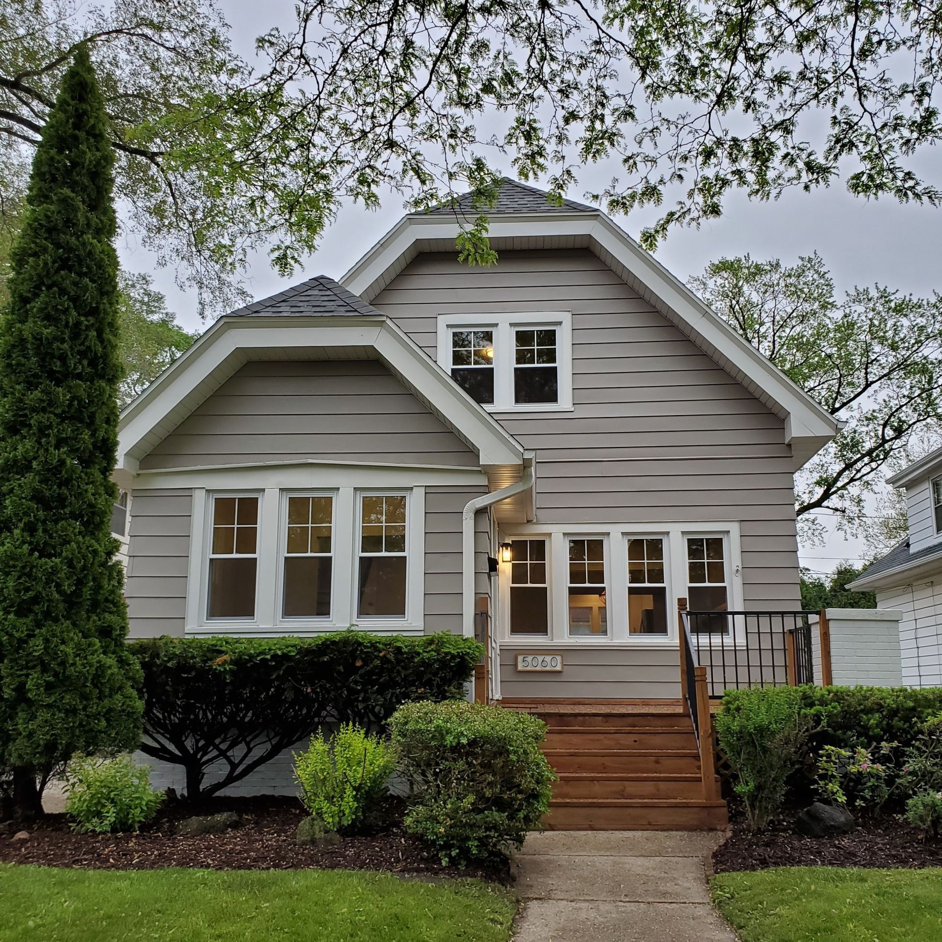 a brick house with a gray siding and white windows