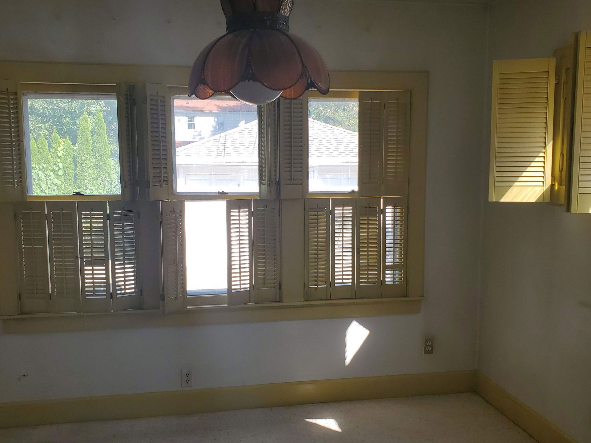 an empty basement with a light on the ceiling and a window .