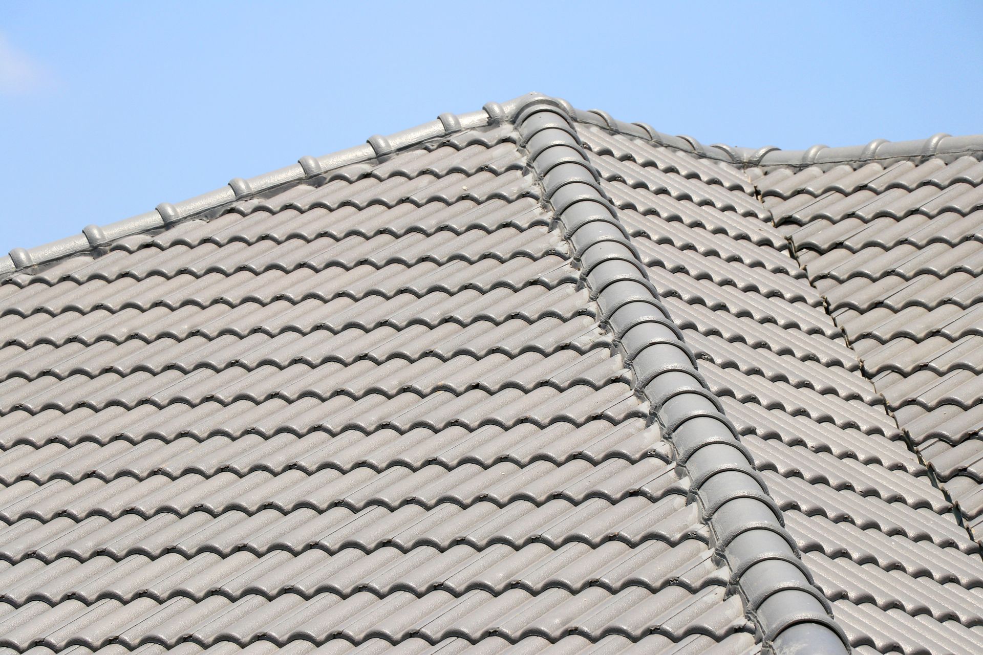 Gray tiled roof under a clear blue sky, with a diagonal ridge line visible