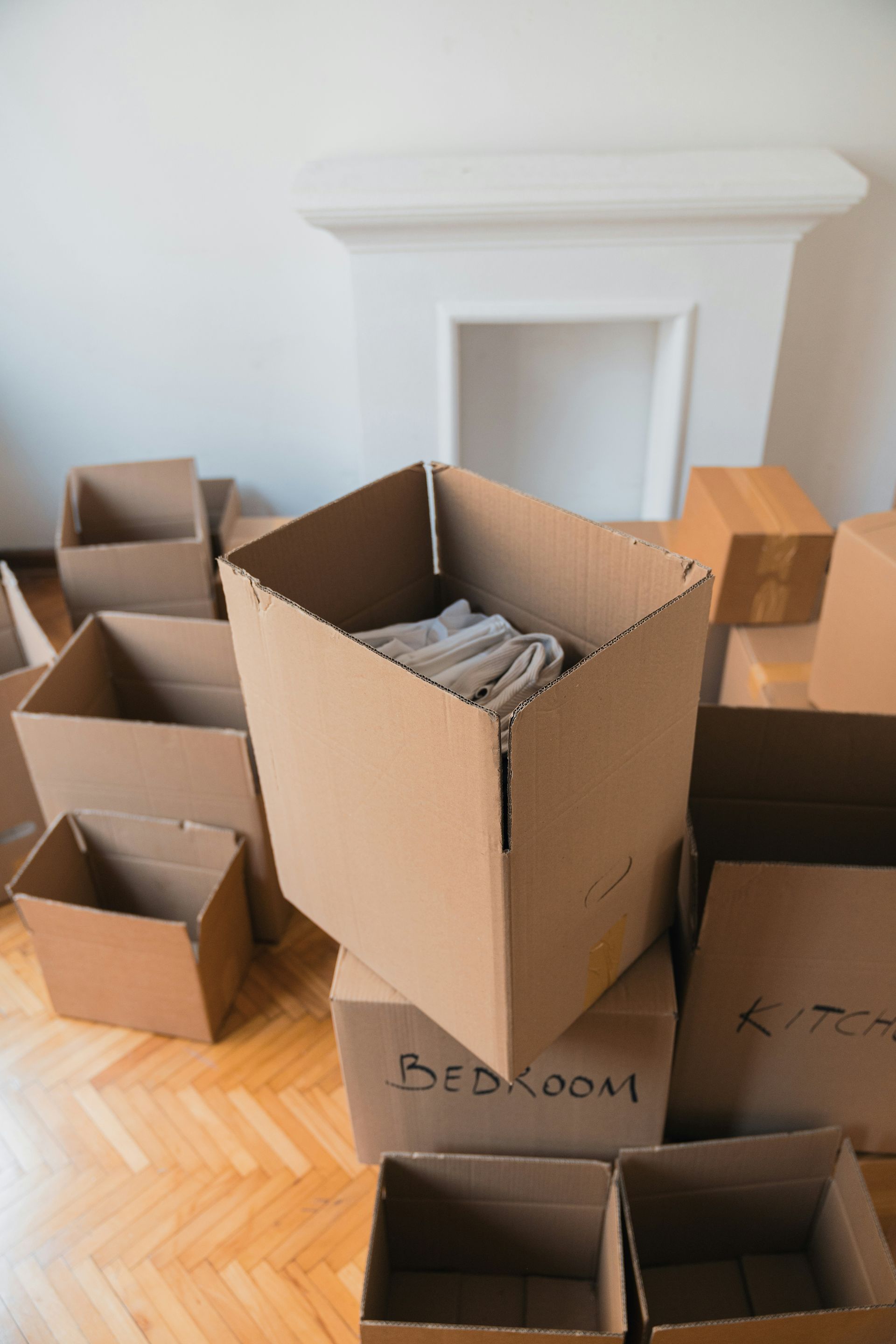 Empty white fireplace with cardboard boxes on the floor.