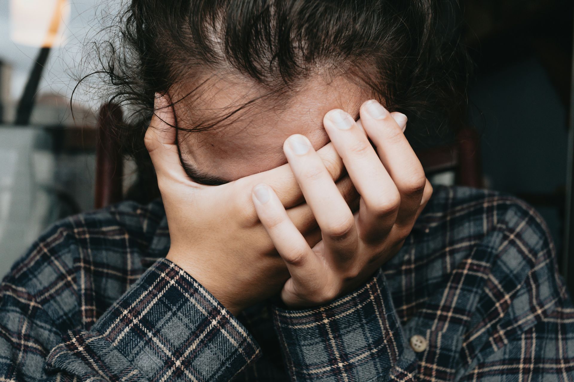 A child with both hands covering their face because they are unhappy