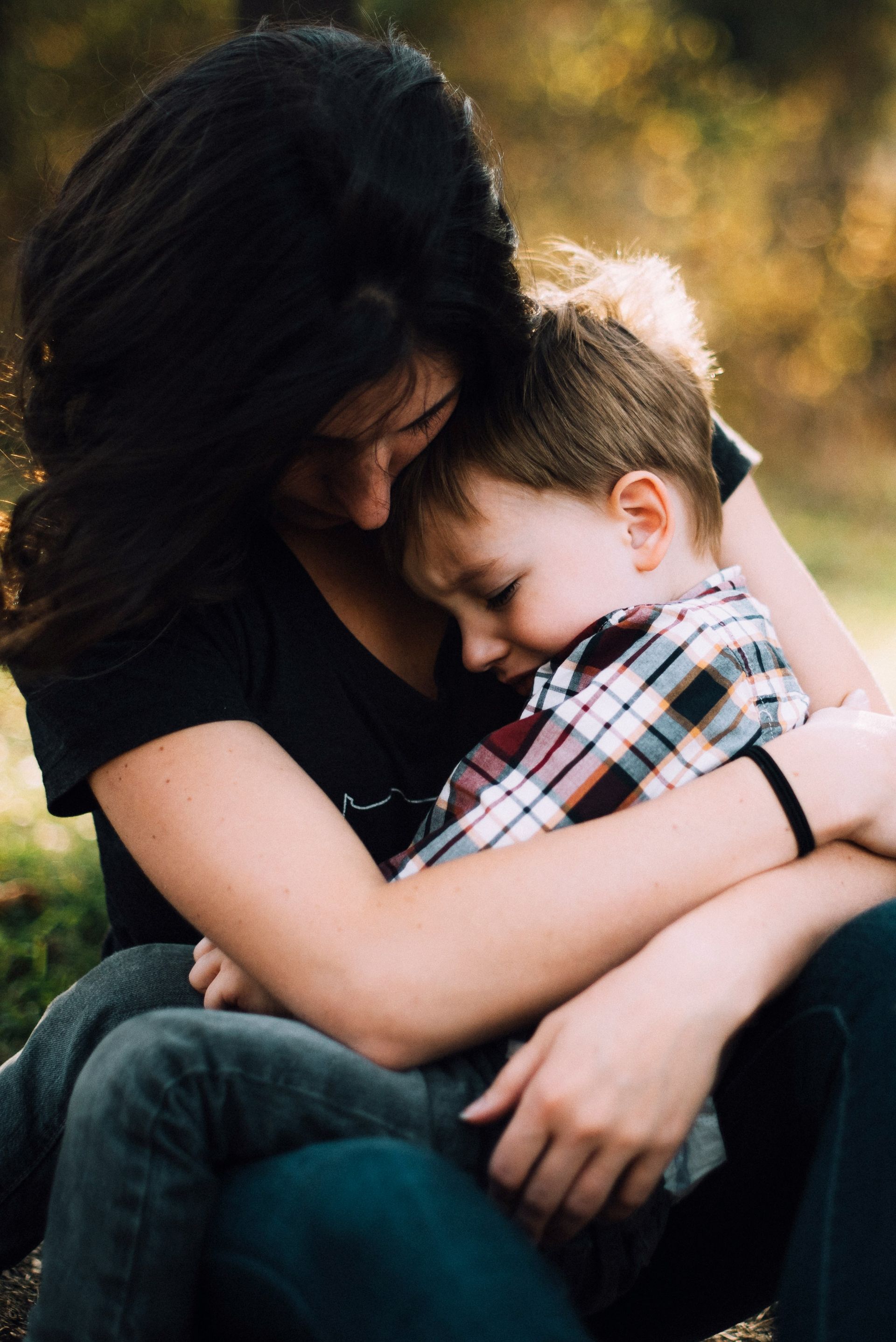 Mother holding and hugging her child that is crying because they are anxious.