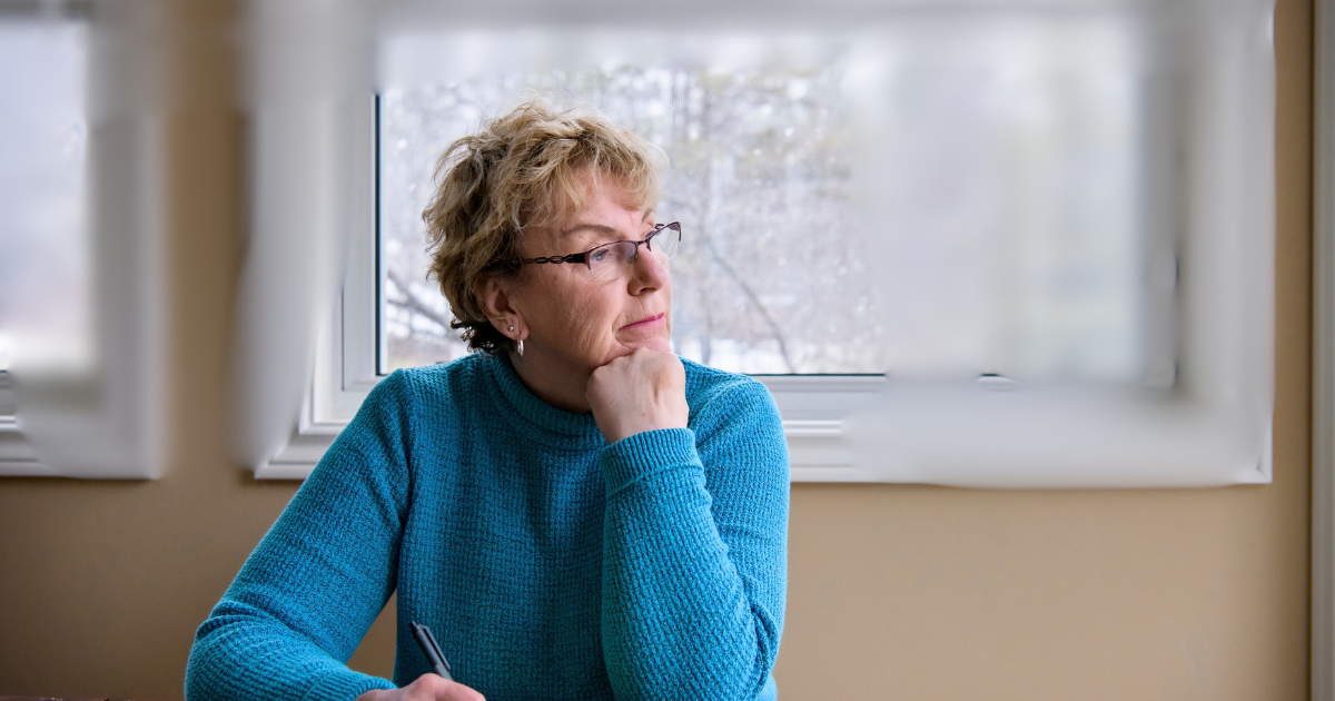 Woman writing in a journal by a window, reflecting on her thoughts and feelings while learning to manage anxious attachment.