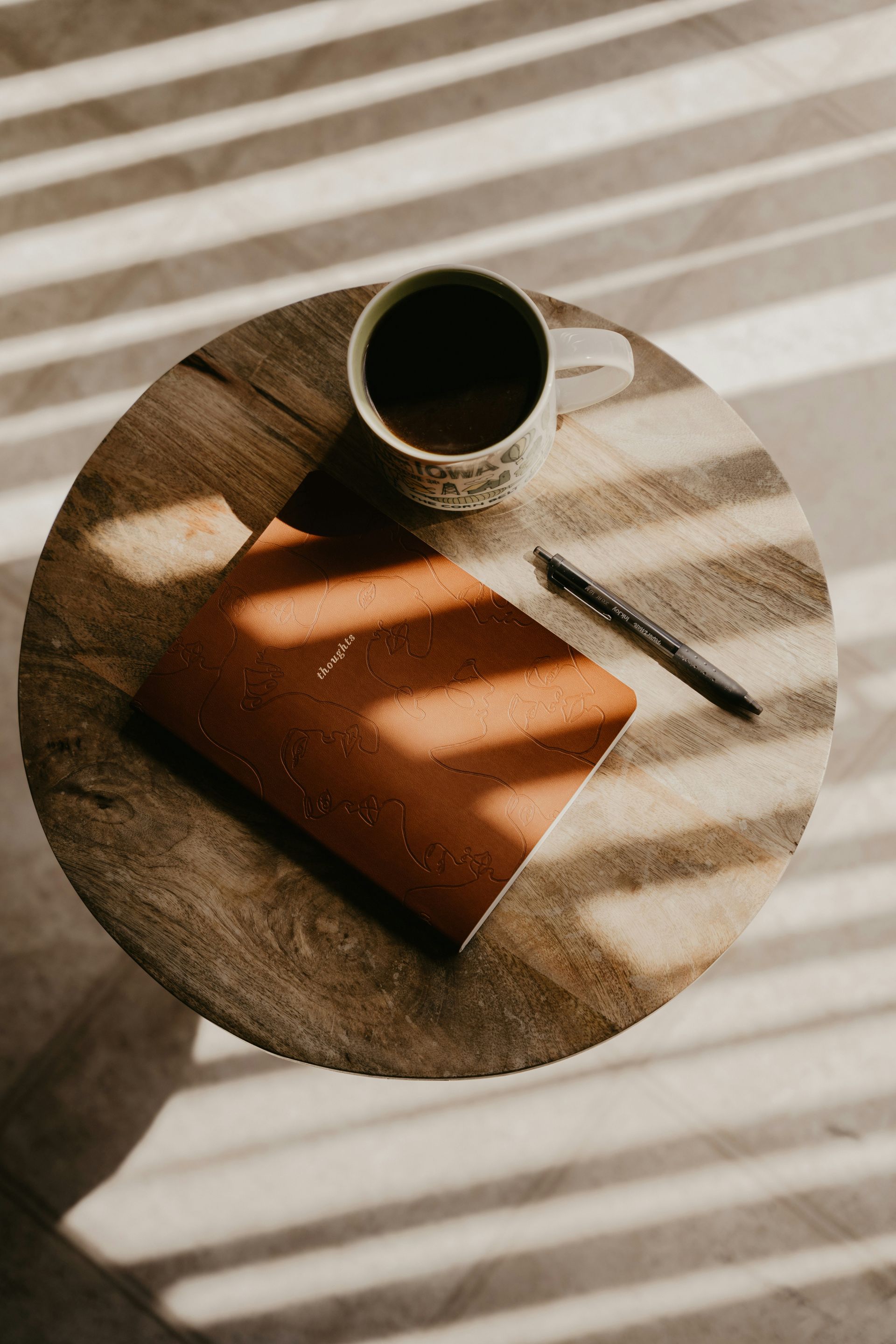 Coffe mug, journal and pen on a round table