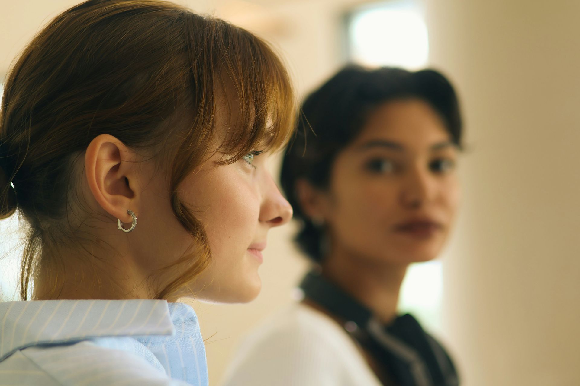 Two women sit together, one watching the other closely, representing anxious attachment and monitoring another person's mood.