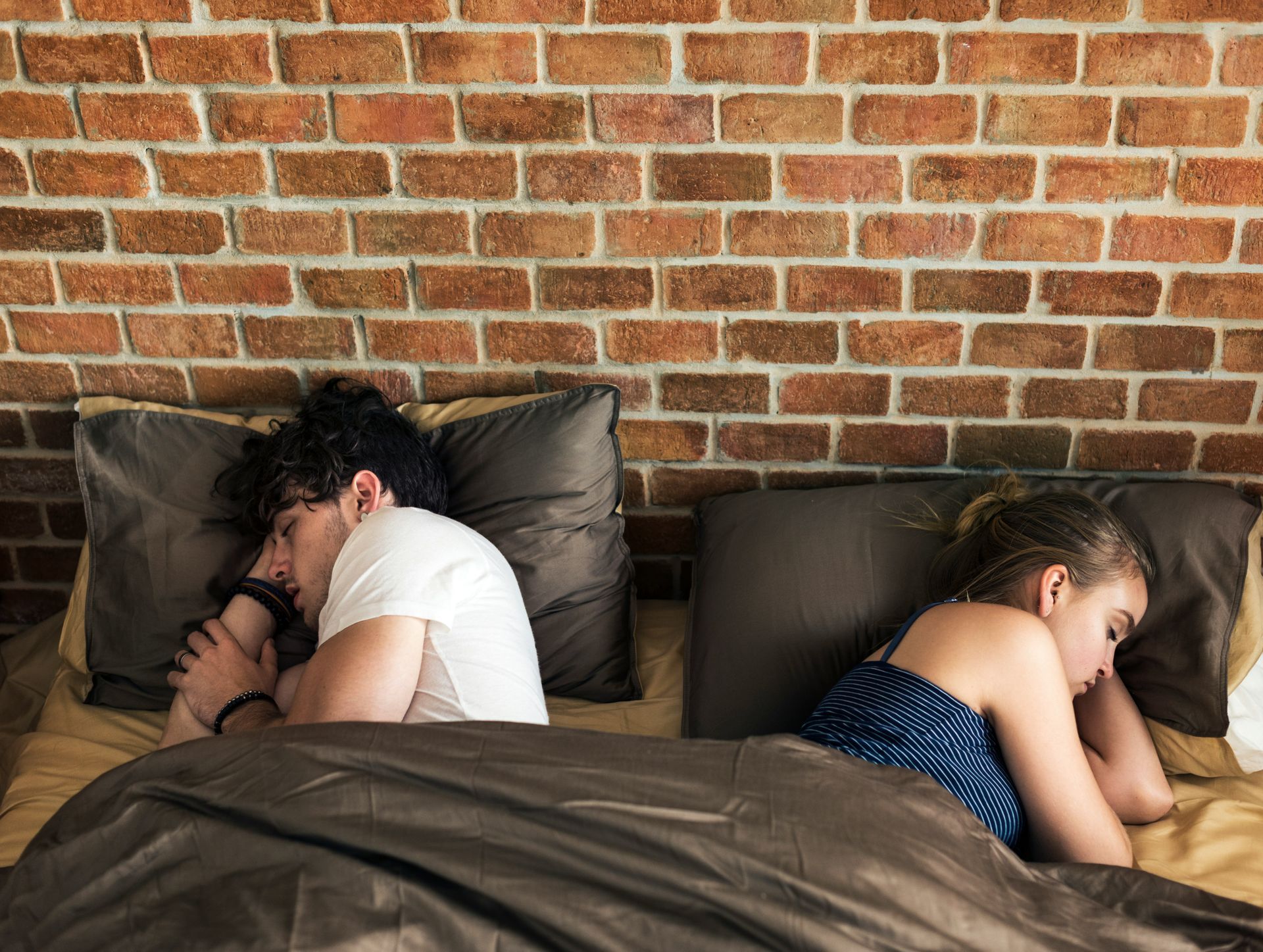 Two partners in bed, facing away from each other, giving the silent treatment