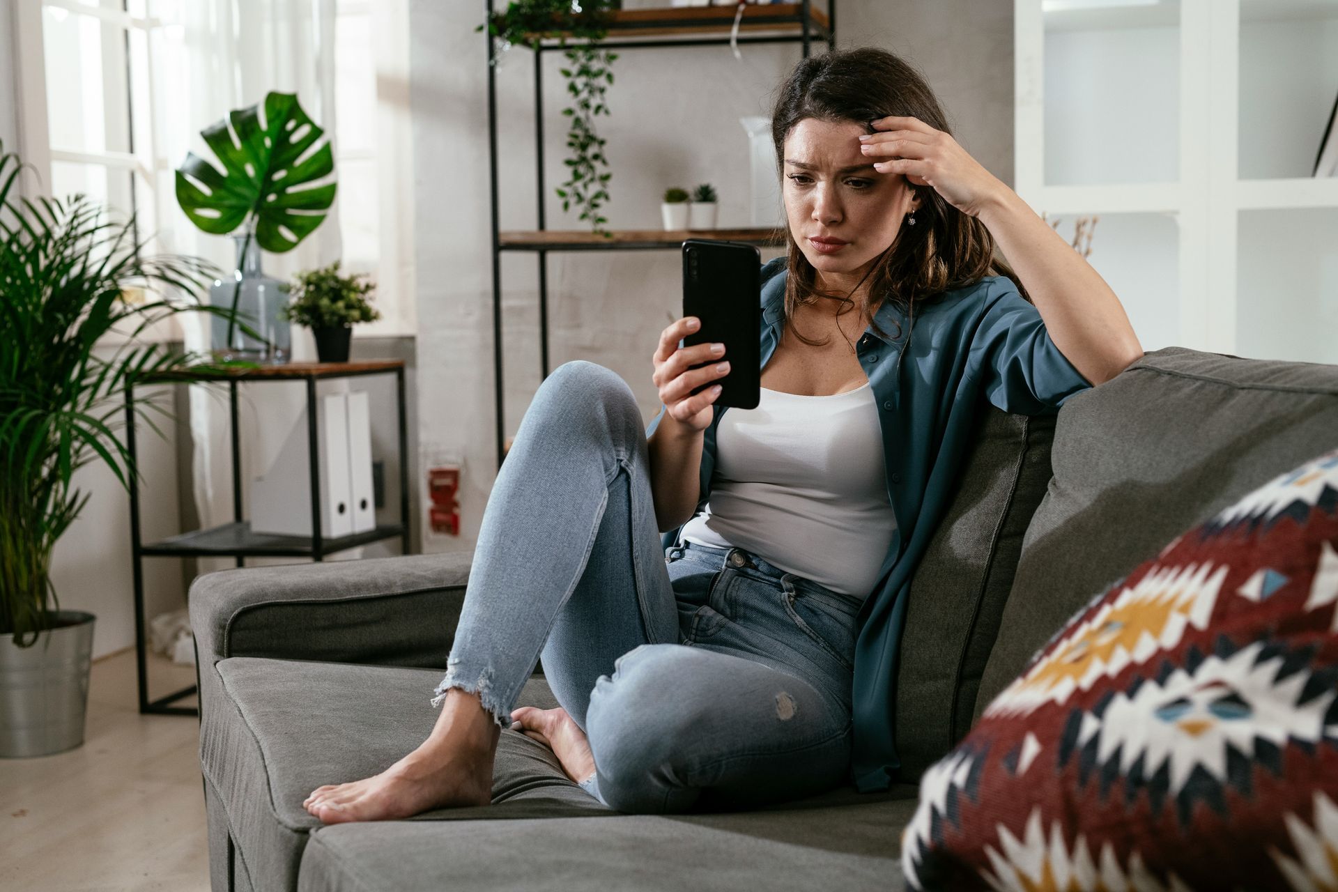 Woman looking anxiously at her phone, representing anxious attachment and the need for reassurance.