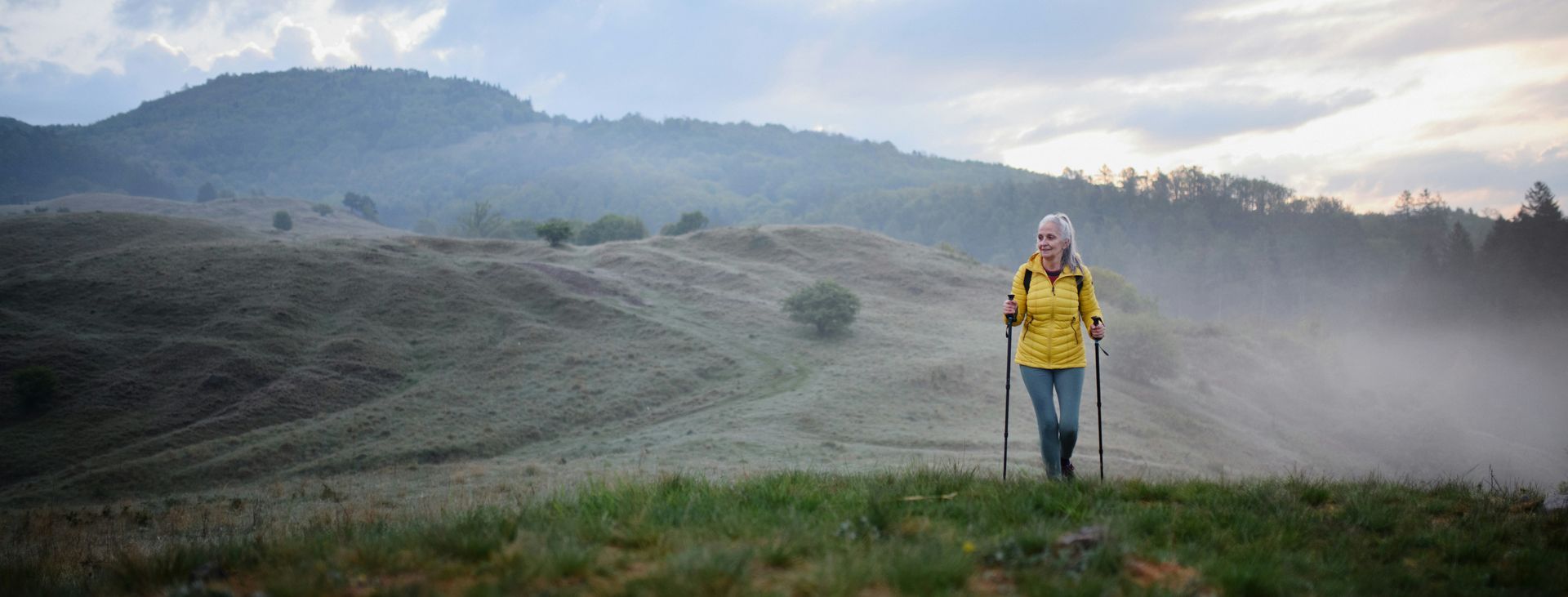 Woman walking outdoors with hiking poles, reflecting confidence, independence, and moving forward after chronic fawning.