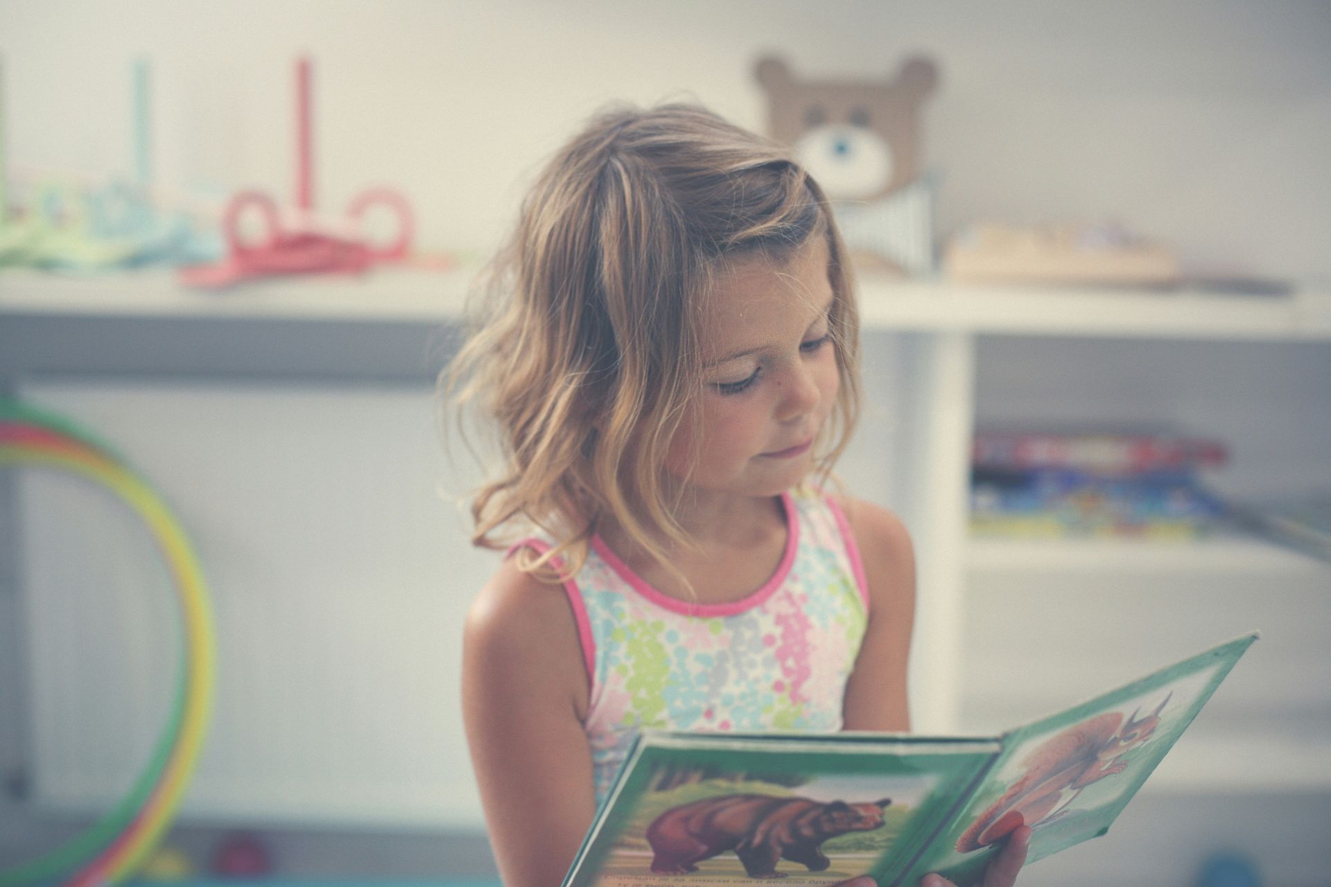 Young elementary-aged girl looking down at a book and practising reading independently.