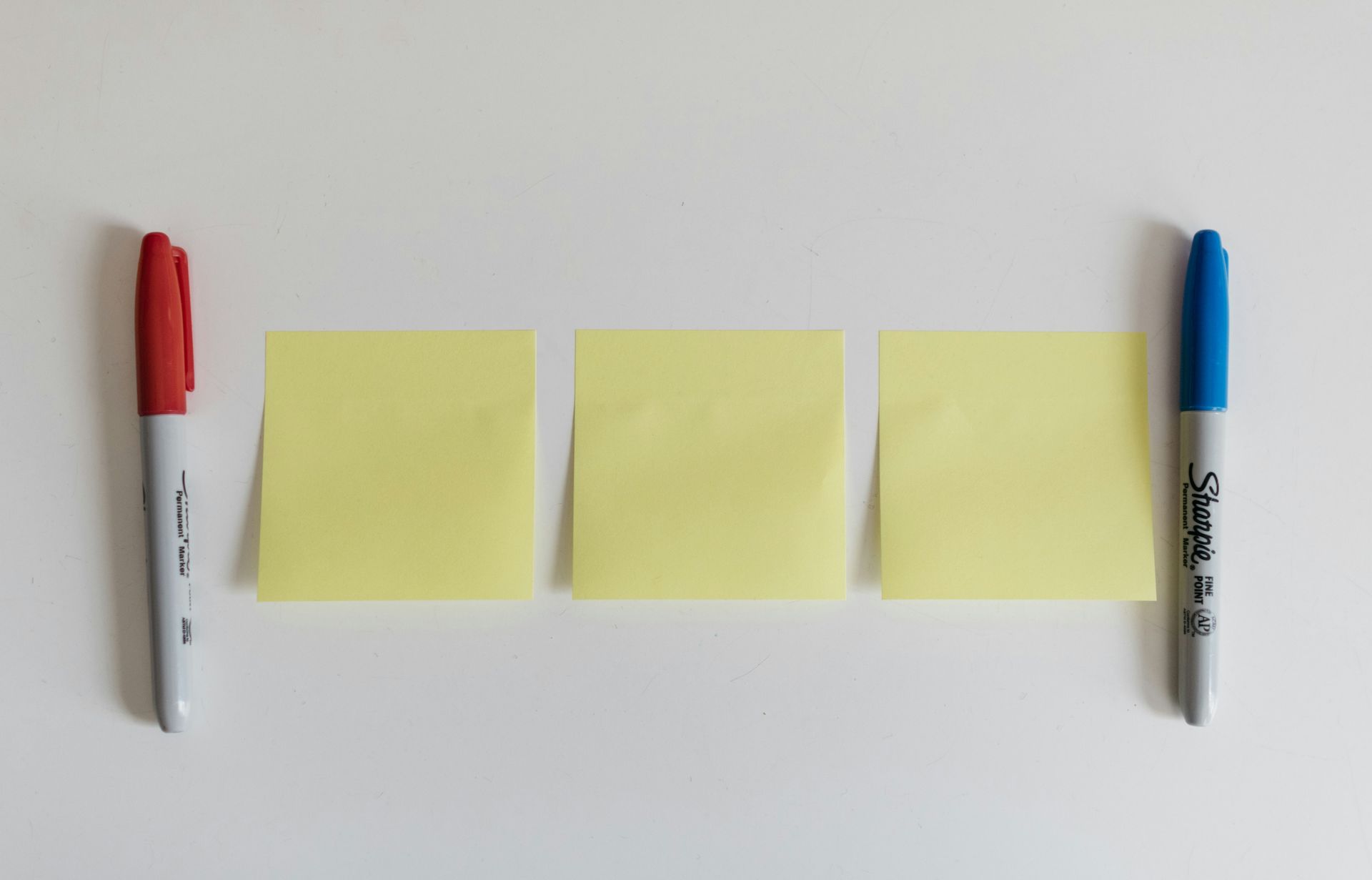 Yellow sticky notes and coloured markers arranged on a white surface for practising sight words and early reading skills.