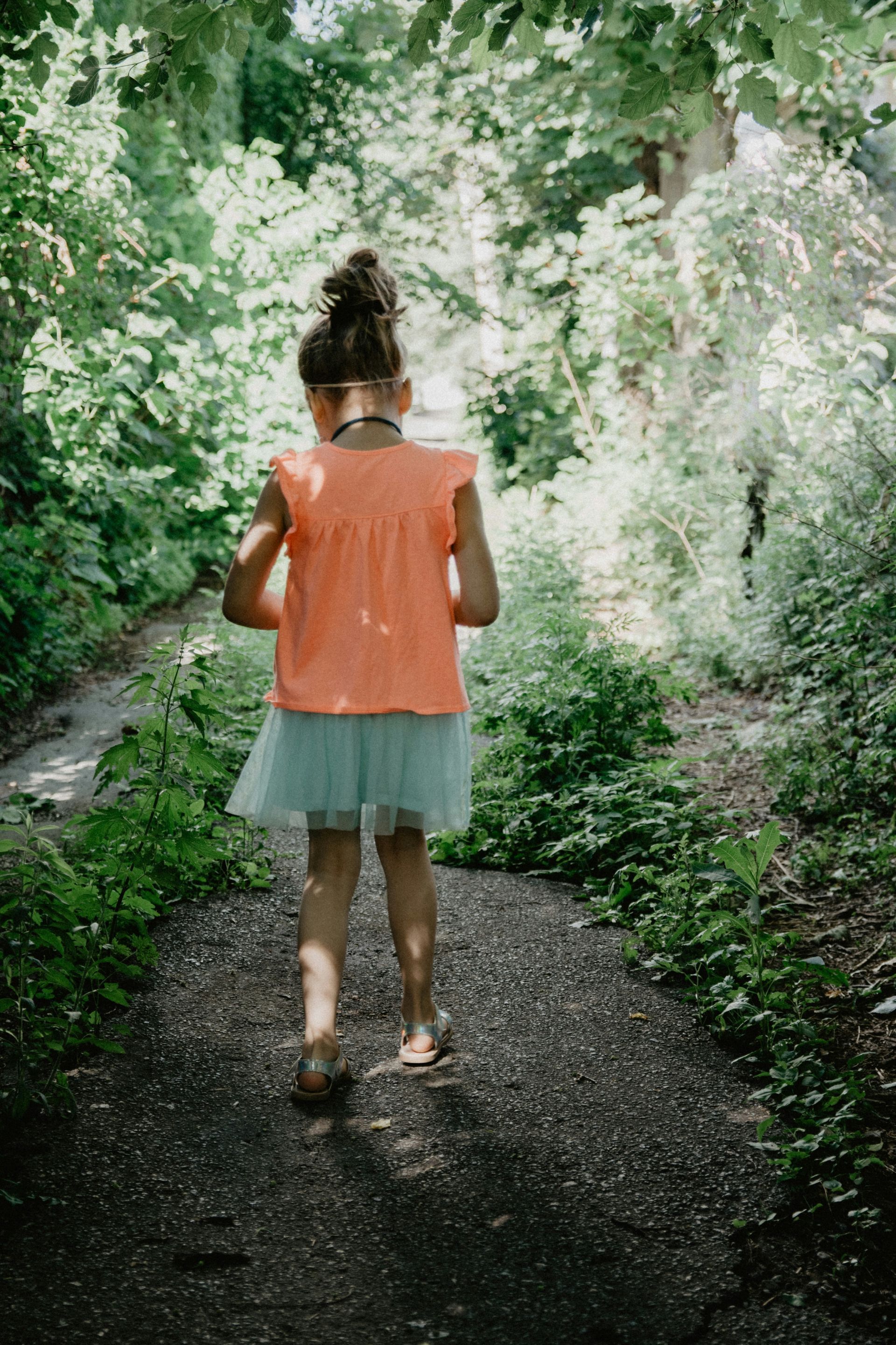 A little girl is walking on a stony path wearing flip-flops.