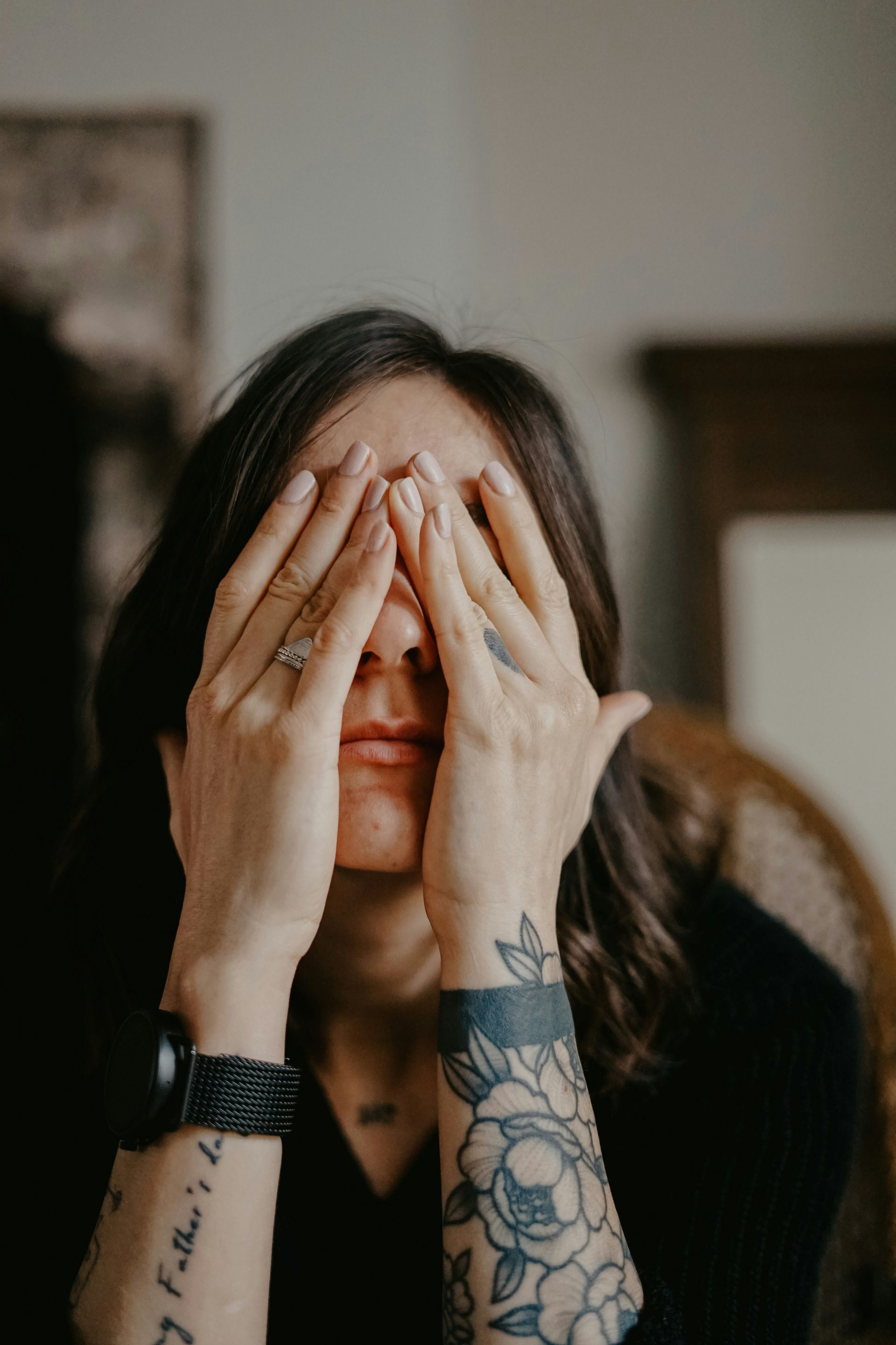 A person sitting with their hands covering their face, expressing emotional overwhelm.