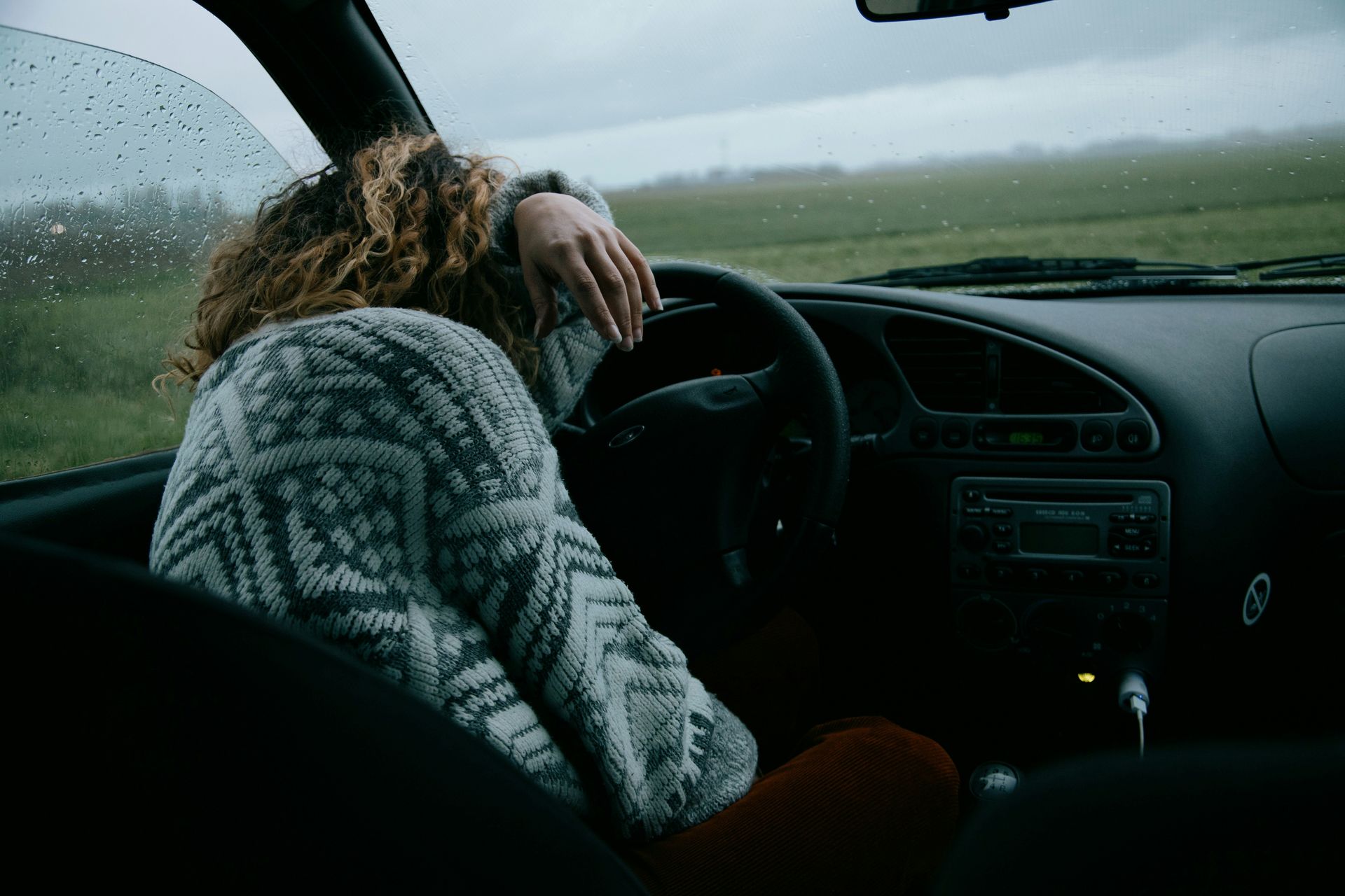 A woman curled up in the passenger seat of a car after a family gathering. The image represents emotional hurt, self-doubt, and recovery from unhealthy family relationship patterns.