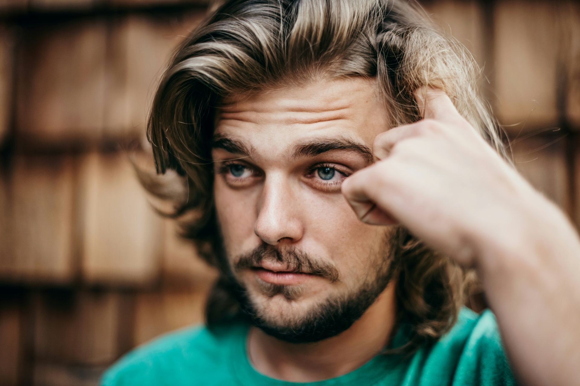 A man deep in thought, touching his temple, represents self-doubt and overthinking.