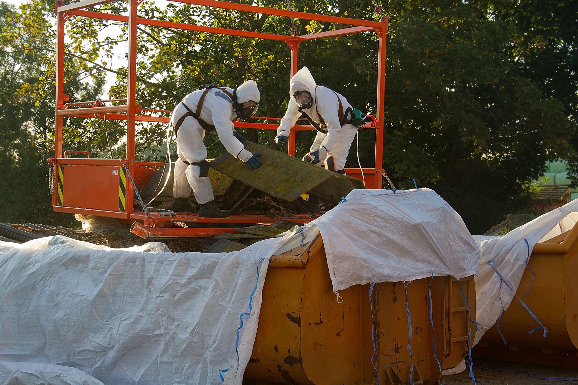 Two men are removing an asbestos corrugated roof Two men are removing an asbestos corrugated roof.