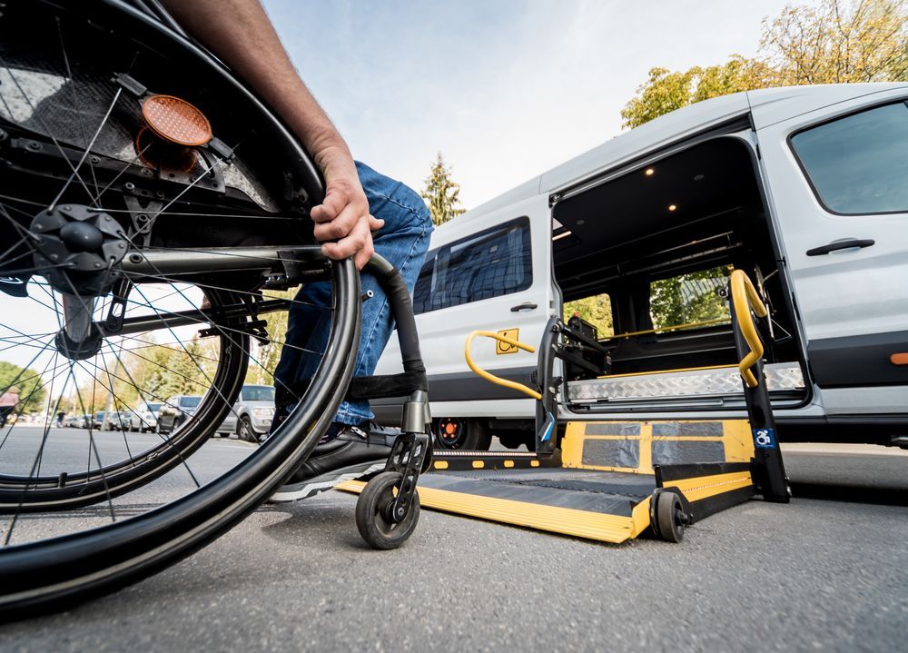 Wheelchair being loaded onto a van via a rear lift ramp on a city street.