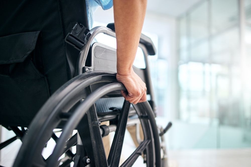 Person pushing a wheelchair down a bright hospital corridor