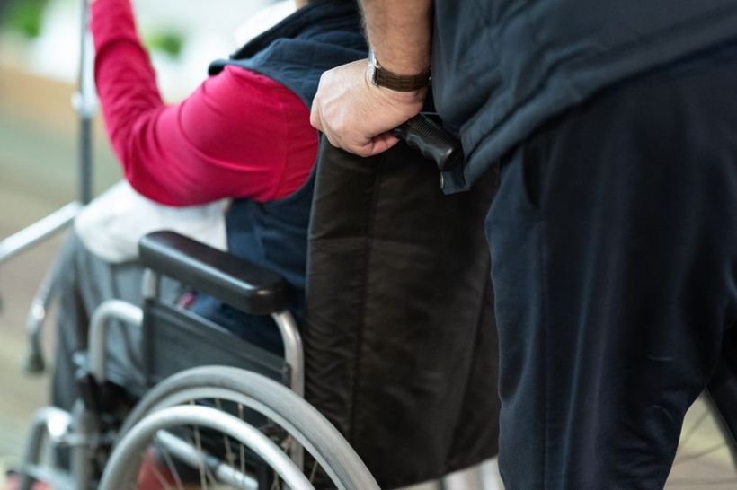 Person in a wheelchair with another person helping them move outdoors